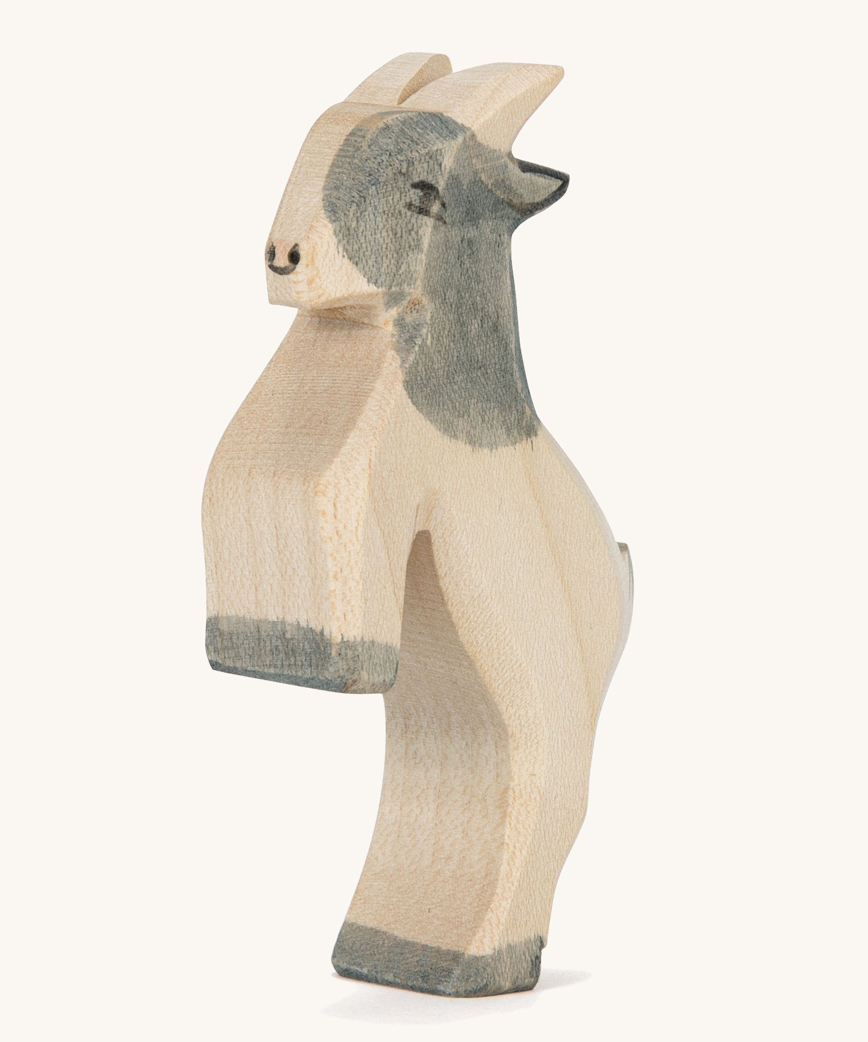 A grey and white wooden Ostheimer jumping goat figure on a cream background.