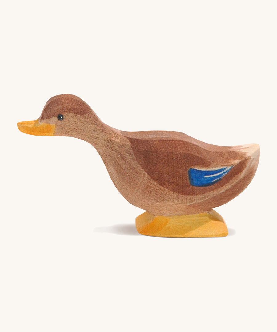 A brown wooden Ostheimer duck with a long neck on a cream background