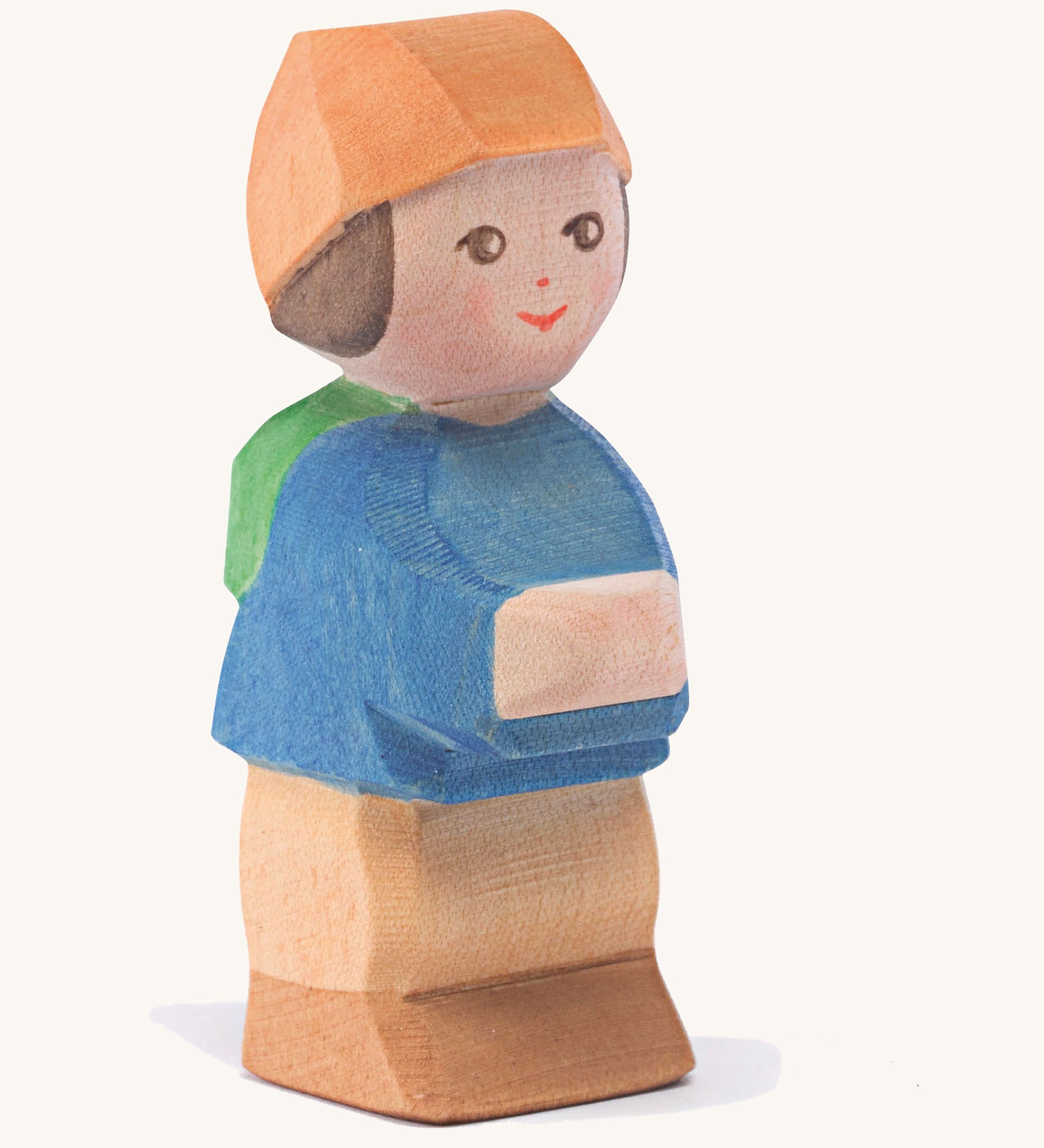 A wooden Ostheimer mo figure wearing a blue coat, orange hat and brown trousers on a cream background.