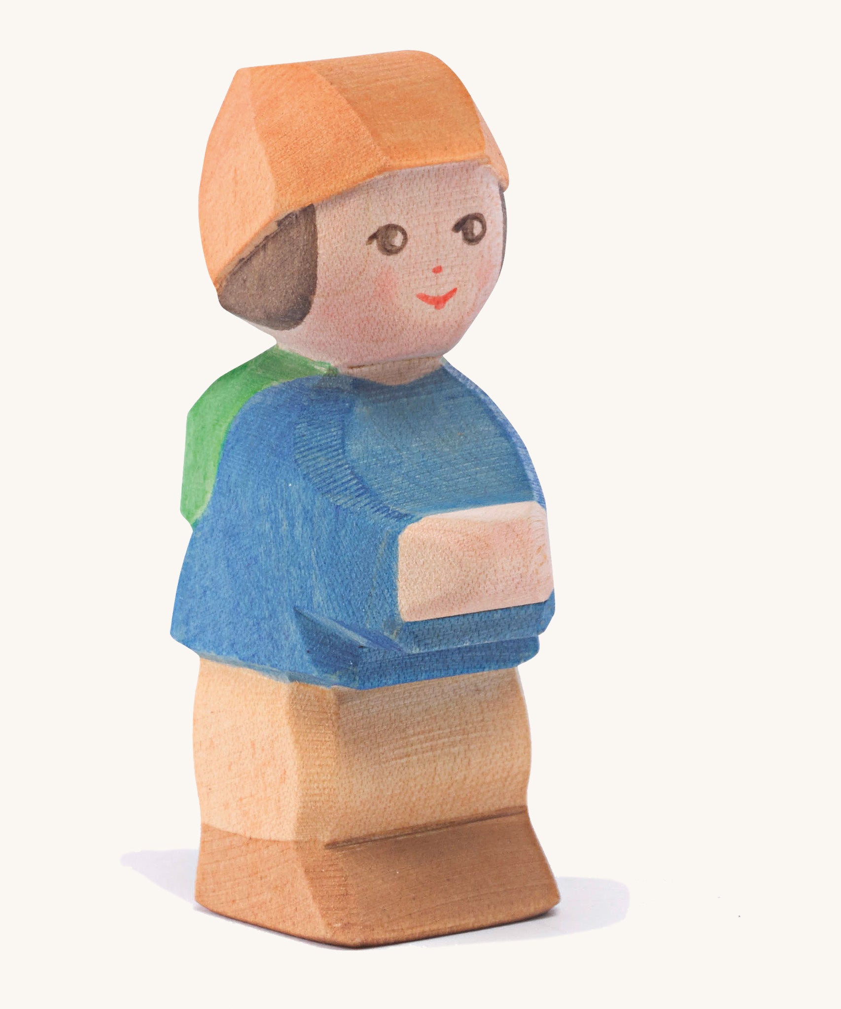 A wooden Ostheimer mo figure wearing a blue coat, orange hat and brown trousers on a cream background.