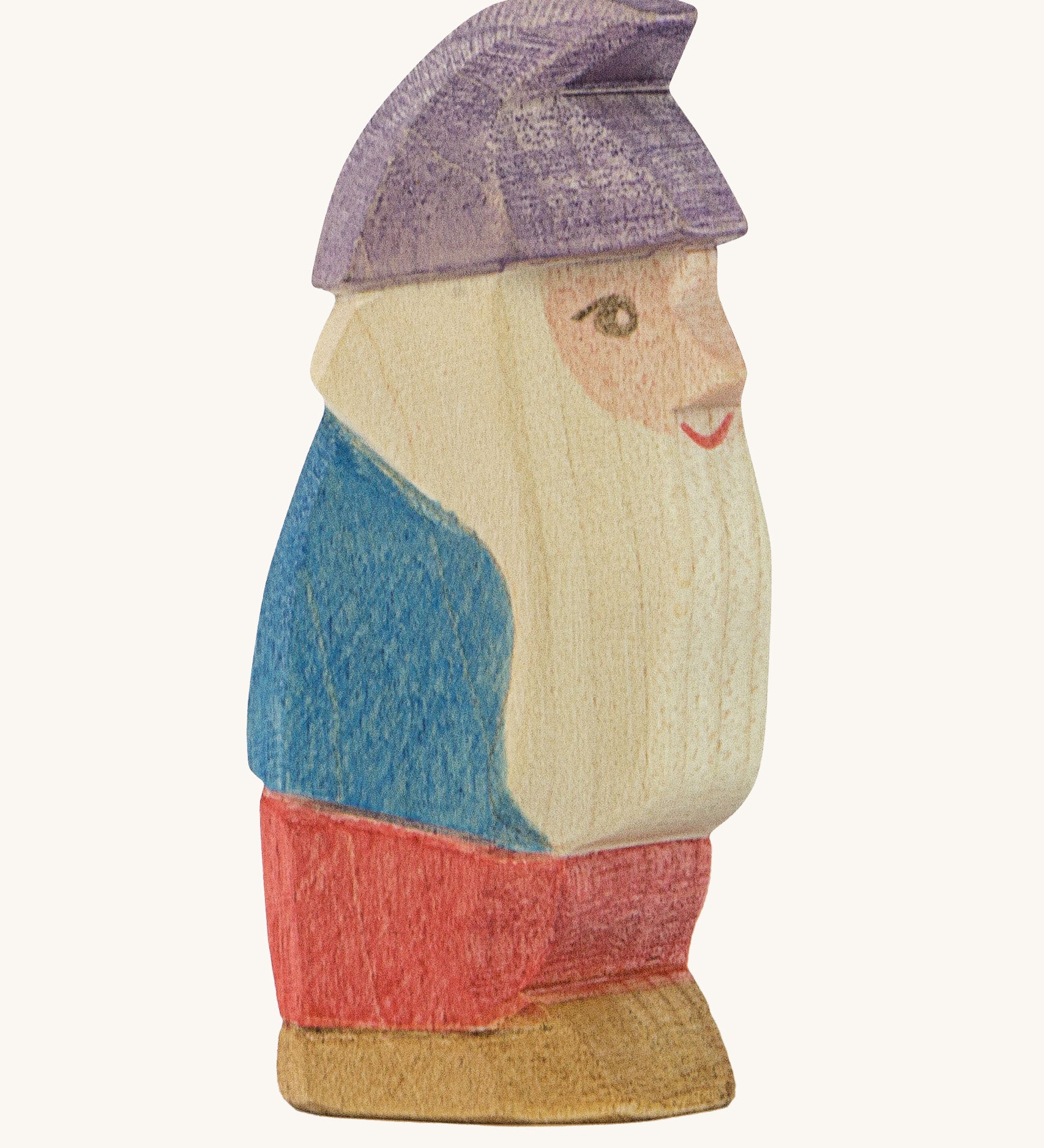 A wooden Ostheimer Paule dwarf figure wearing a blue top, red trousers and a purple hat  on a cream background