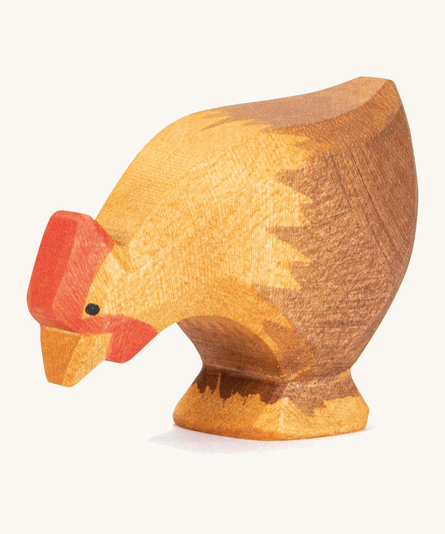 A wooden brown Ostheimer pecking hen figure on a cream background.