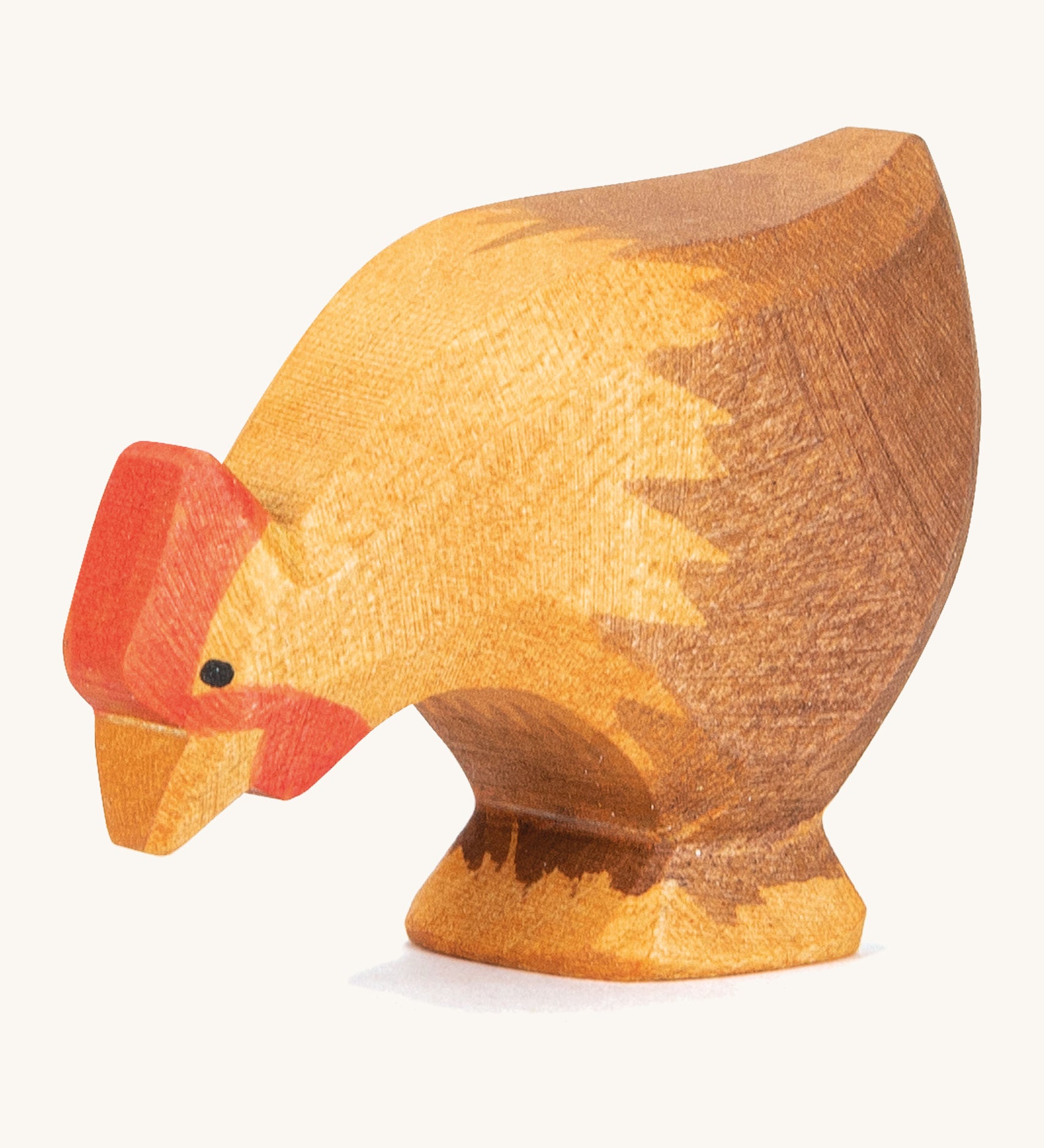 A wooden brown Ostheimer pecking hen figure on a cream background.