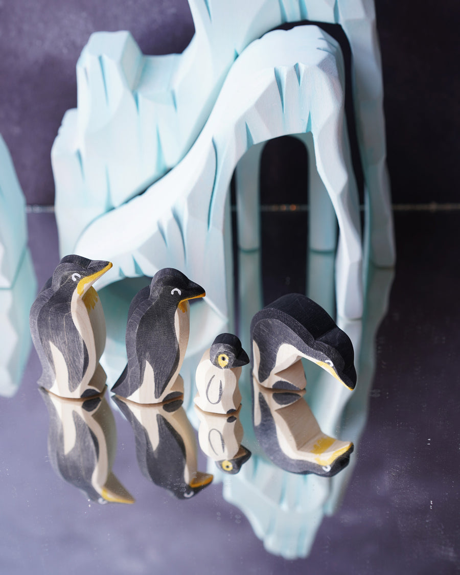 Ostheimer penguin family figures stood on a refelective surface in front of the Bumbu icy cliffs