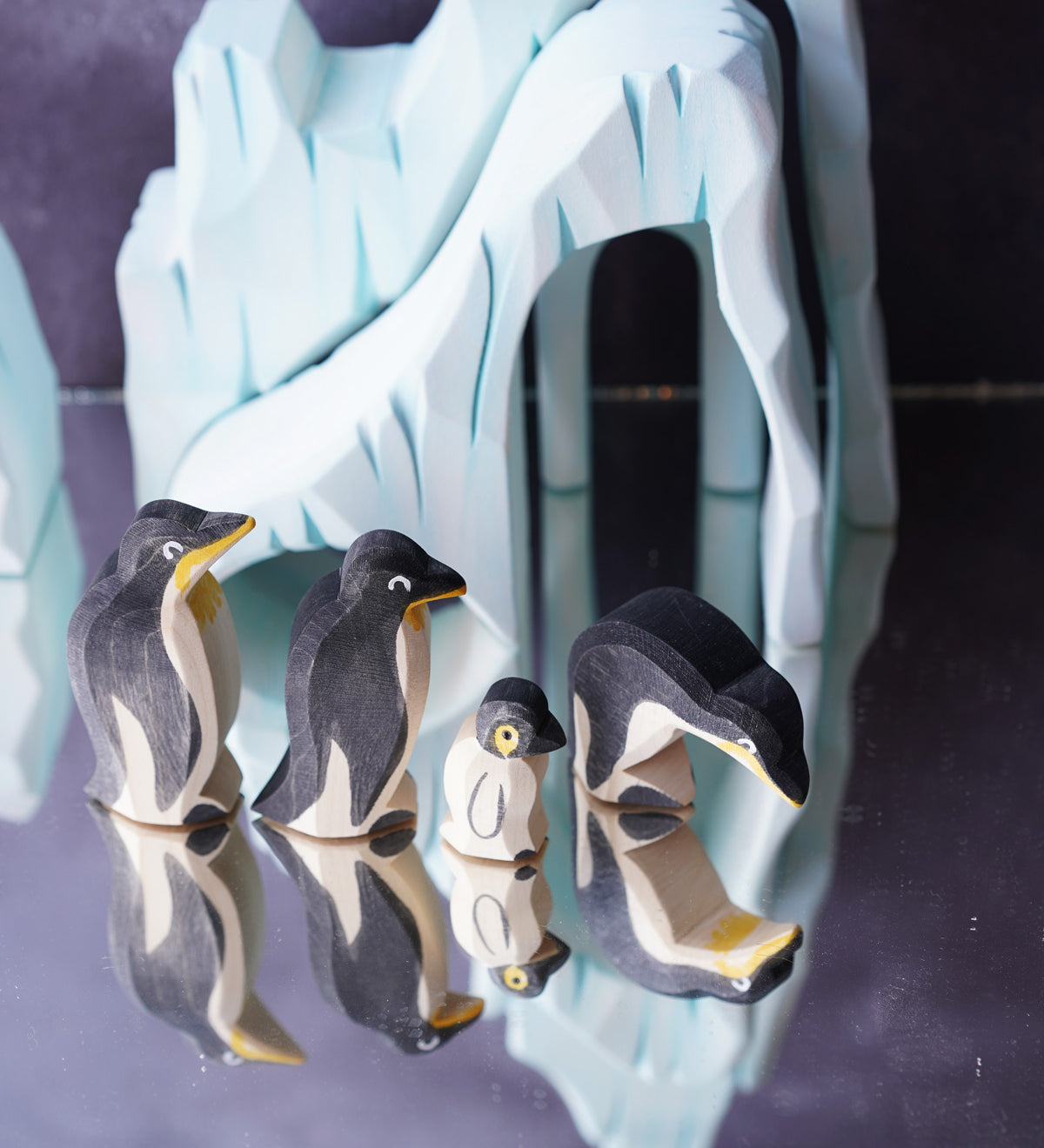 Ostheimer penguin family figures stood on a refelective surface in front of the Bumbu icy cliffs