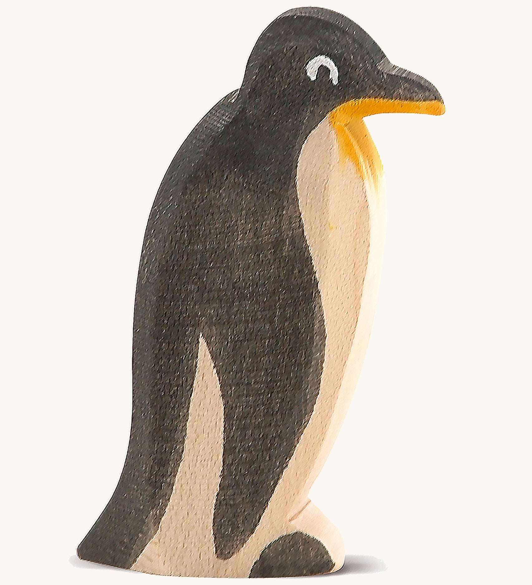 A straight standing wooden Ostheimer penguin figure on a cream background.