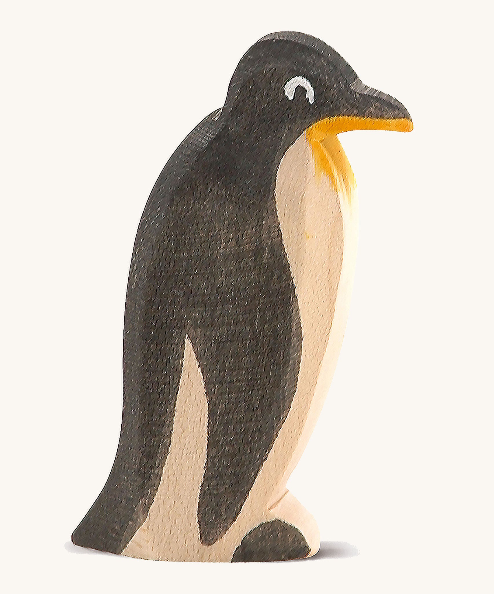 A straight standing wooden Ostheimer penguin figure on a cream background.