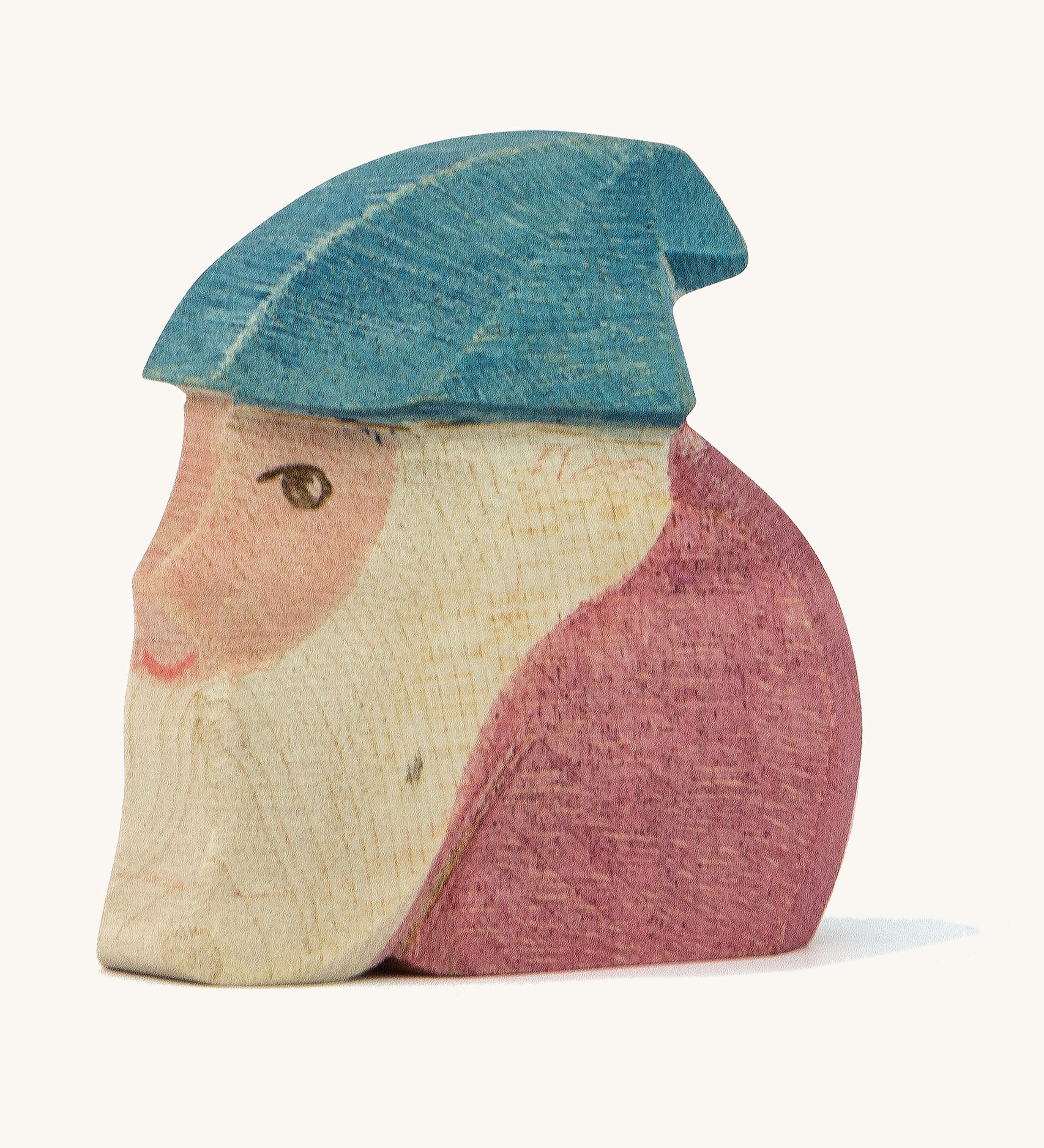 A wooden Ostheimer Peter dwarf figure wearing a purple top and a blue hat on a cream background.