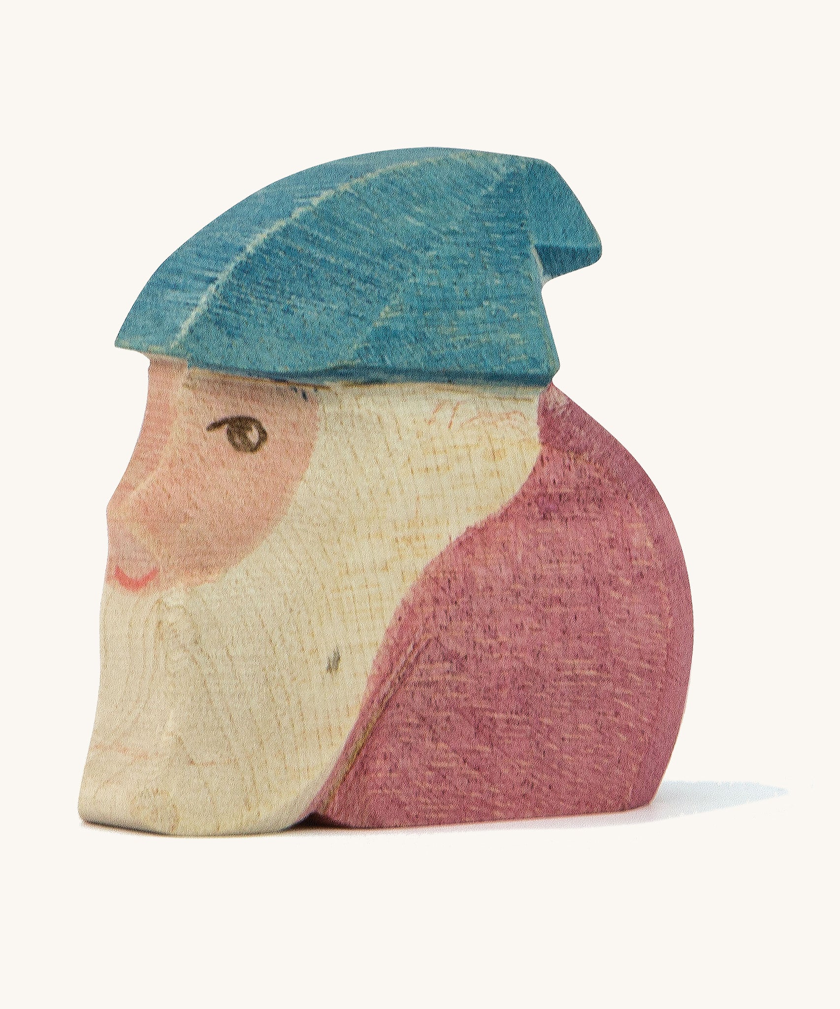 A wooden Ostheimer Peter dwarf figure wearing a purple top and a blue hat on a cream background.