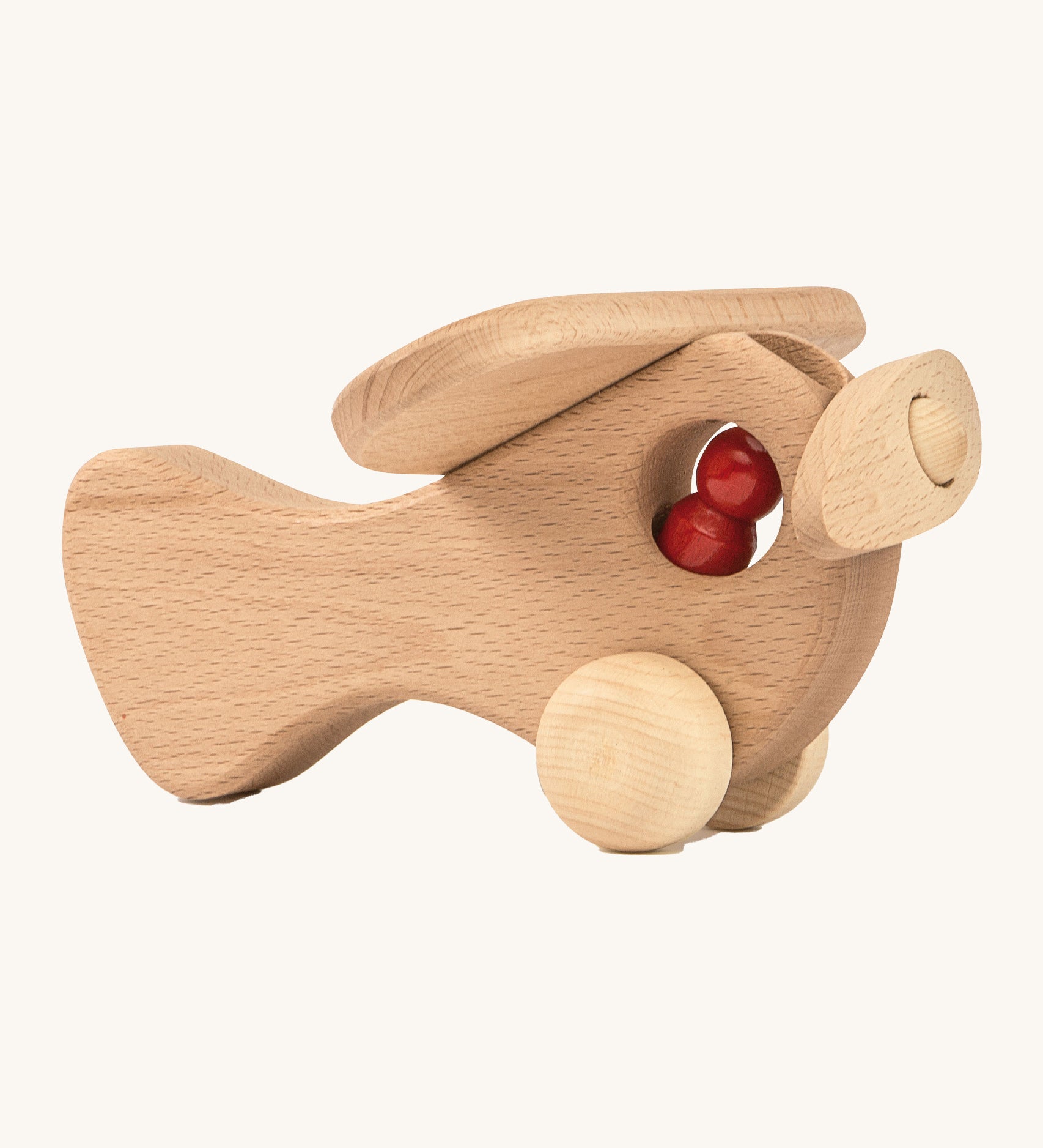 A wooden Ostheimer plane with a red peg doll sitting inside on a cream background.