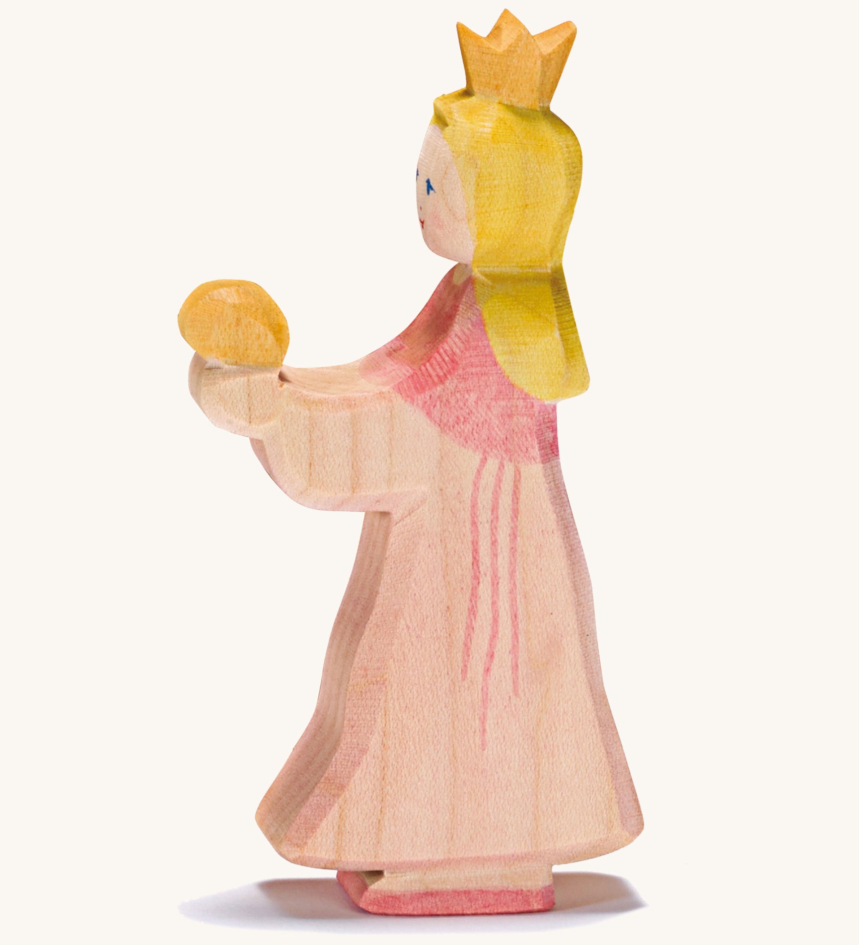 A wooden Ostheimer princess wearing a pink dress with a gold crown on her head on a cream background.