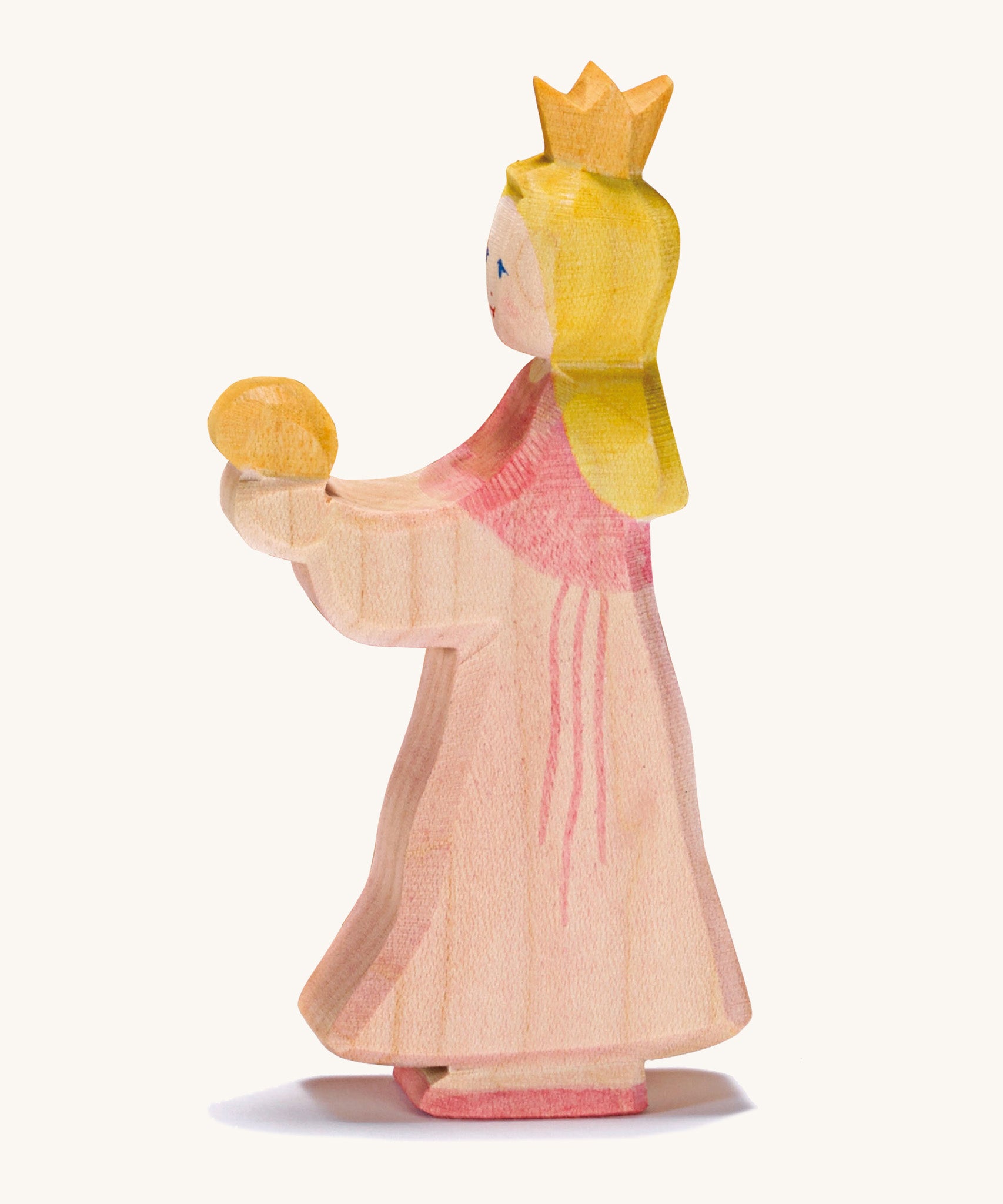 A wooden Ostheimer princess wearing a pink dress with a gold crown on her head on a cream background.