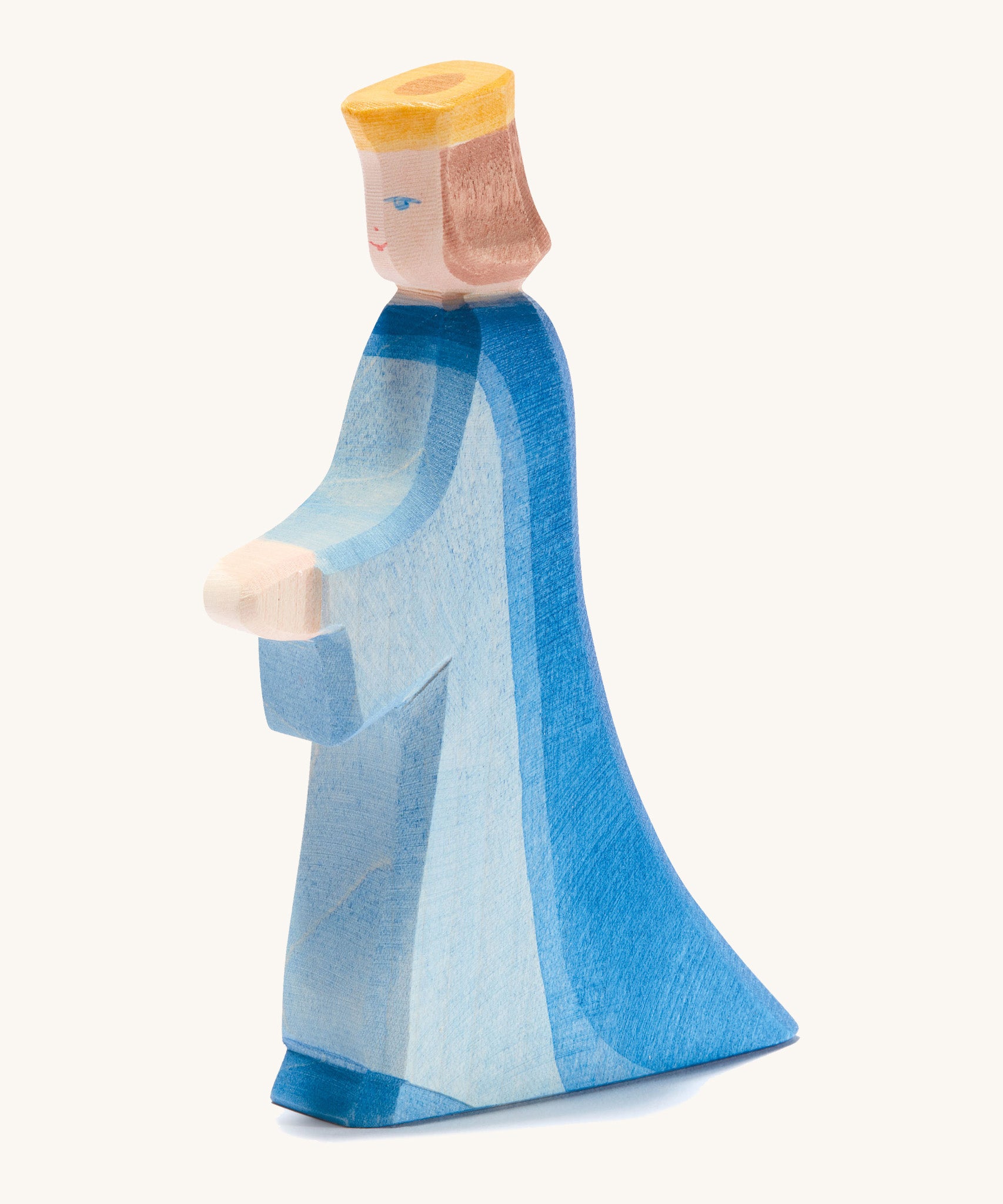 A wooden Ostheimer queen figure wearing a blue flowing dress and yellow crown on a cream background.