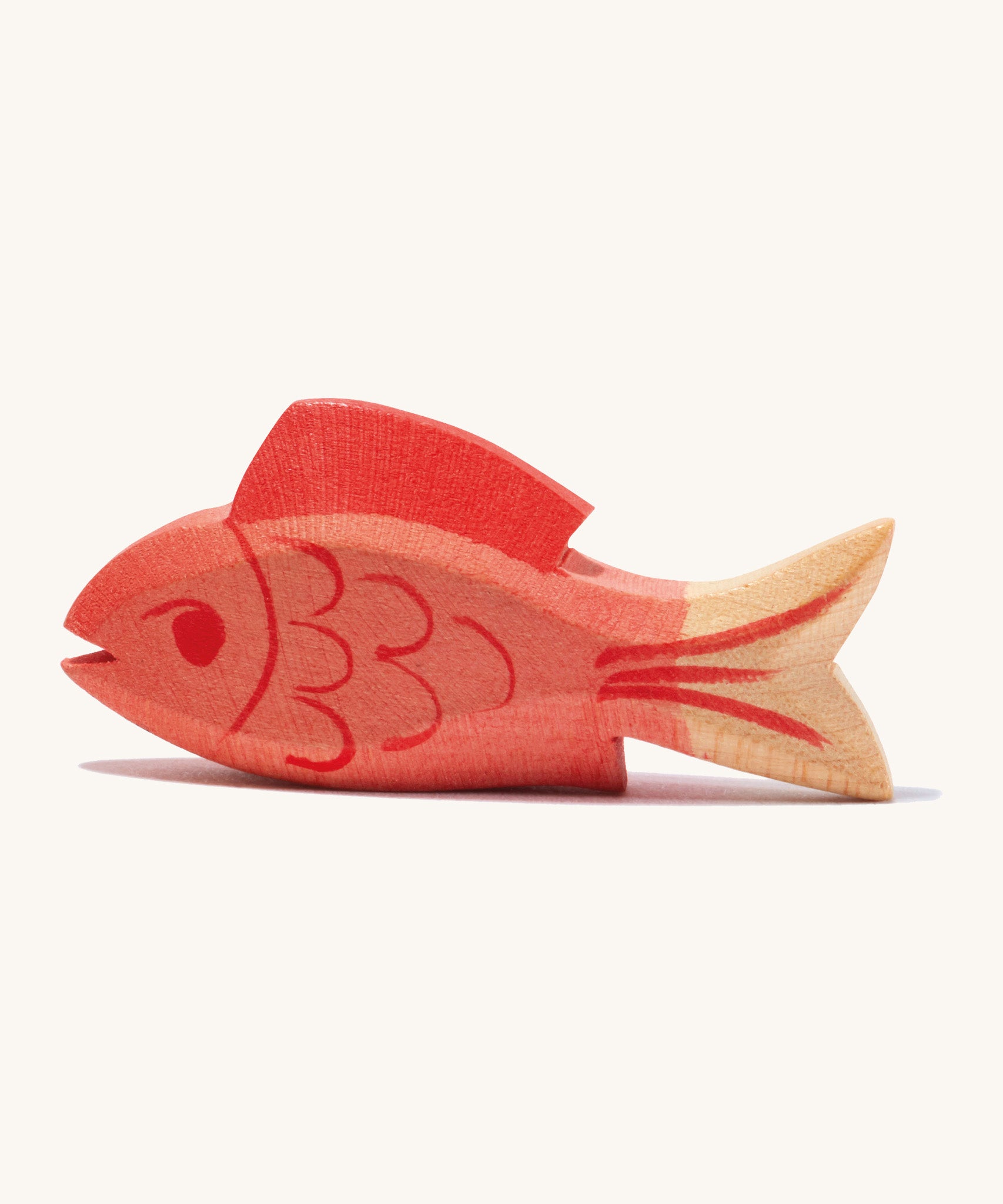 A wooden ostheimer red fish figure on a cream background.