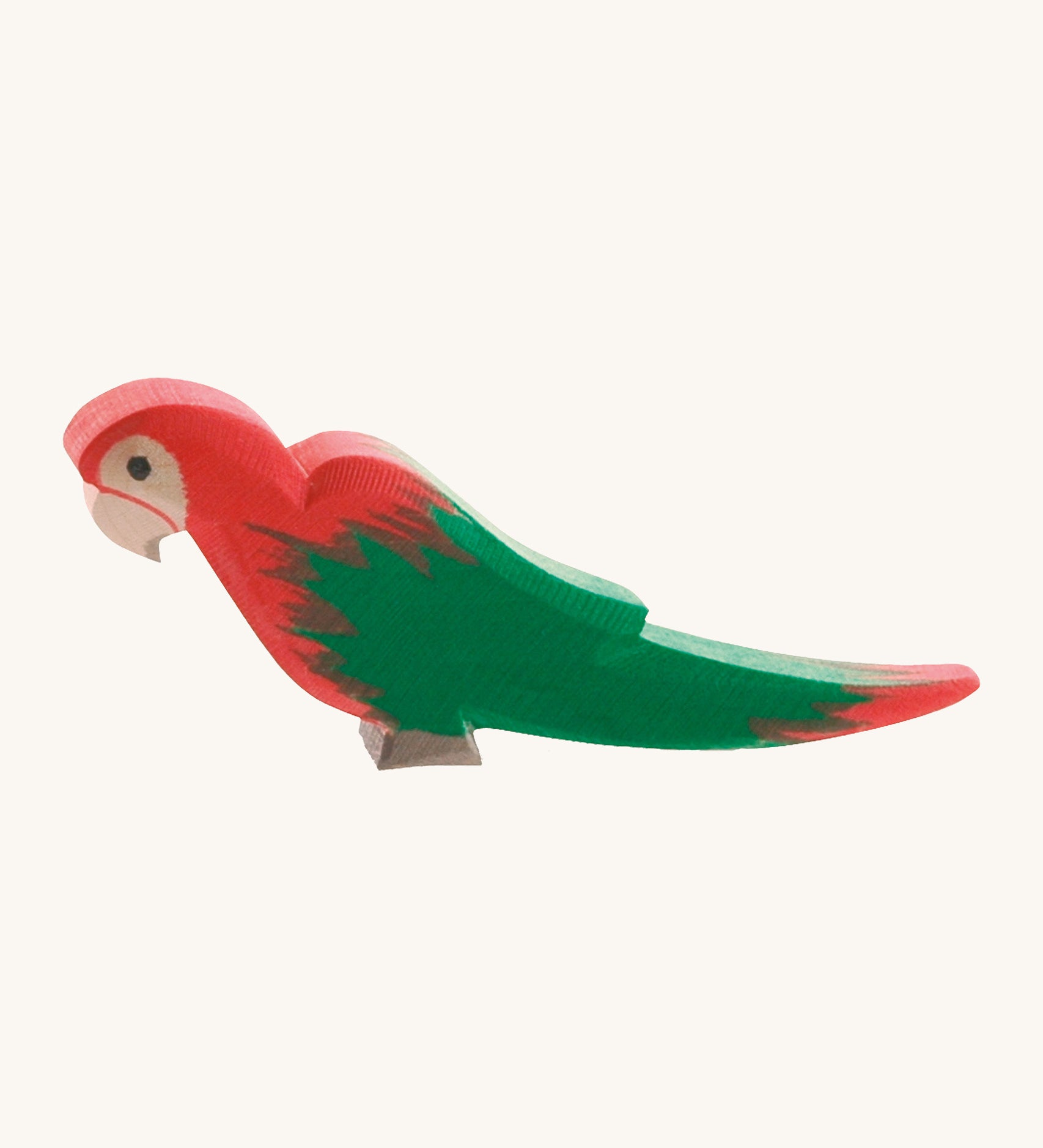 Ostheimer wooden parrot in red, with green wings on a cream background.