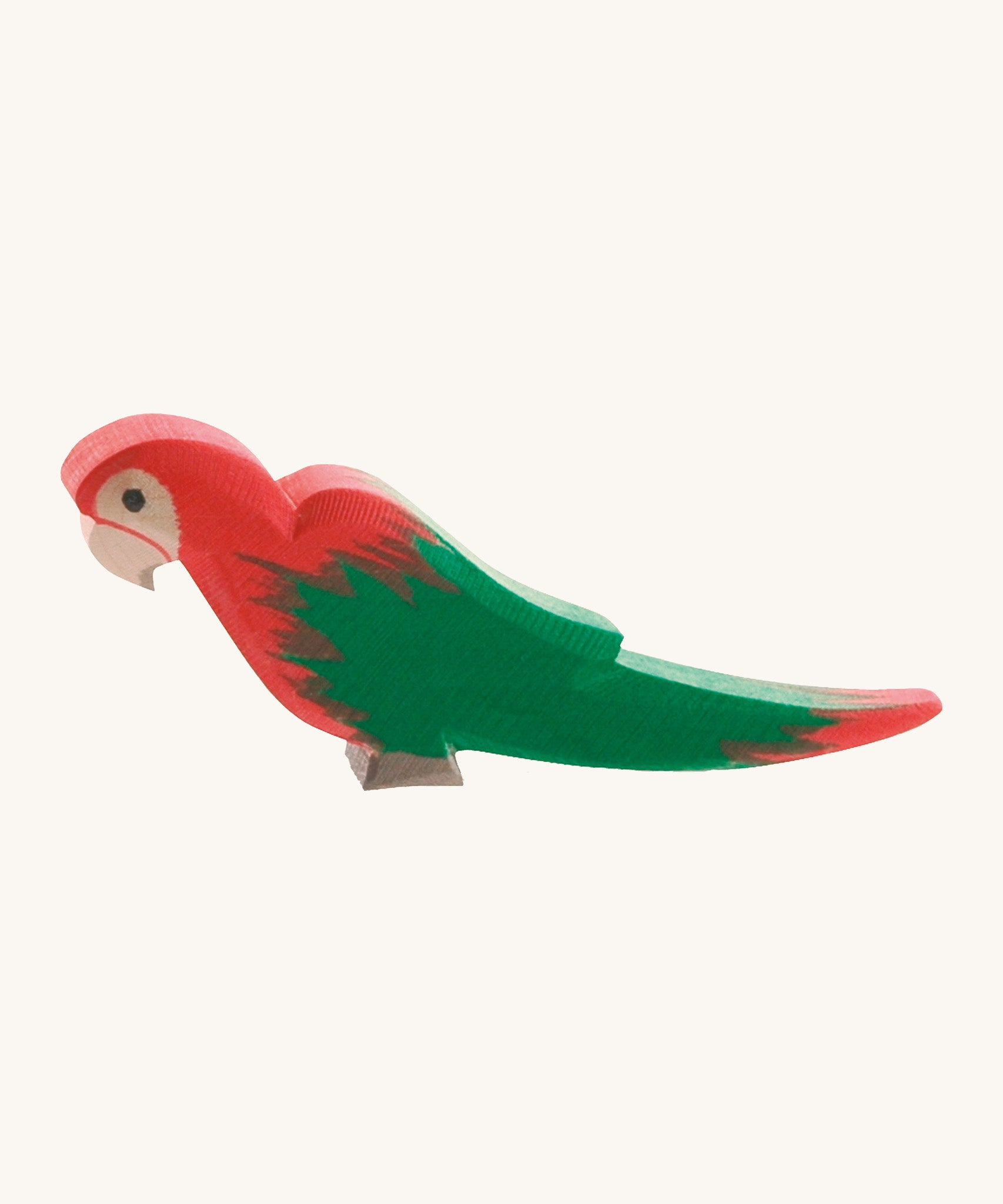 Ostheimer wooden parrot in red, with green wings on a cream background.