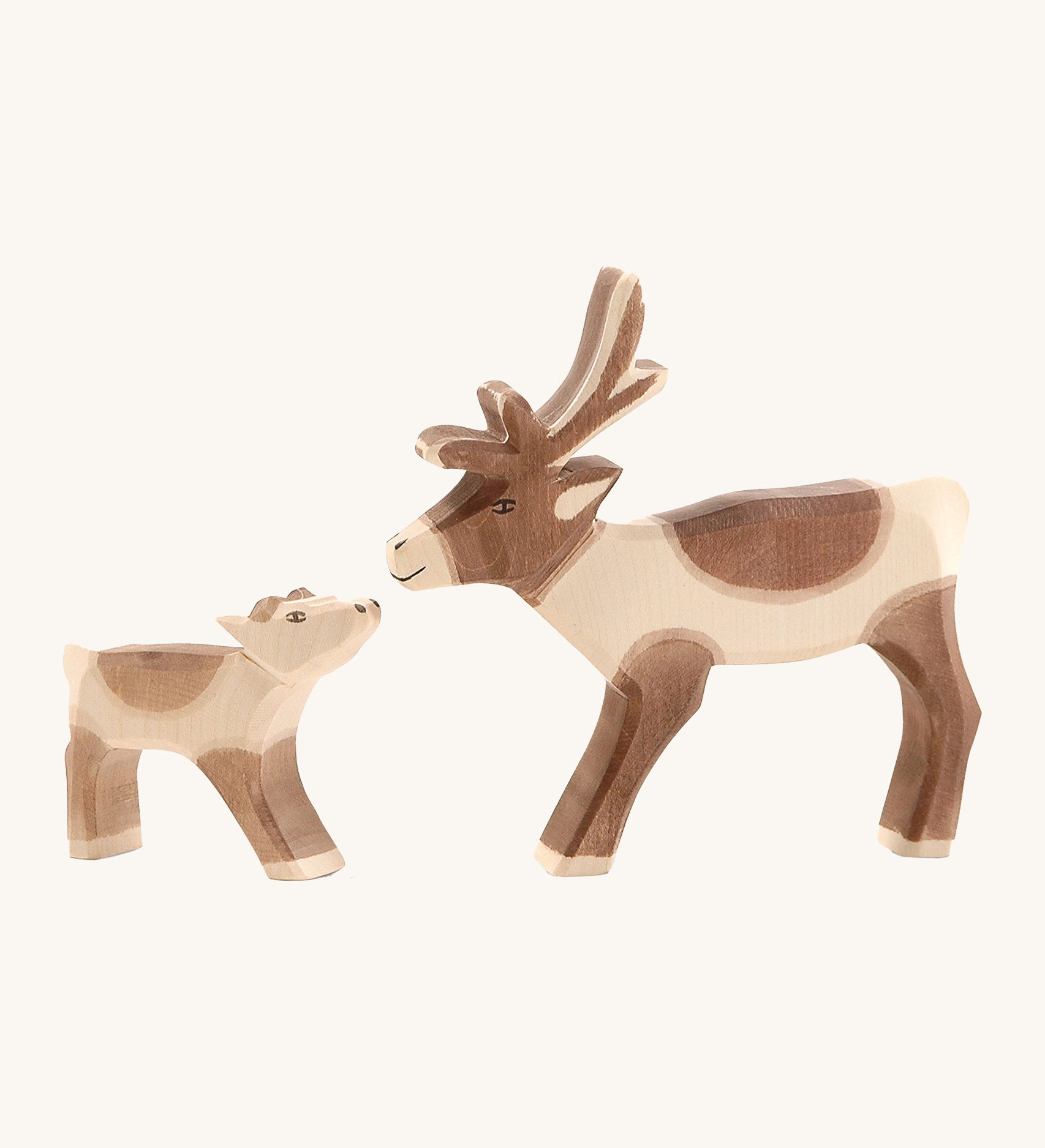 A ostheimer reindeer figure standing next to a wooden Ostheimer reindeer calf on a cream background.