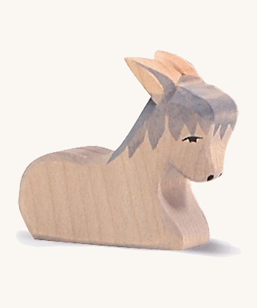 A grey wooden sitting Ostheimer donkey figure on a cream background.