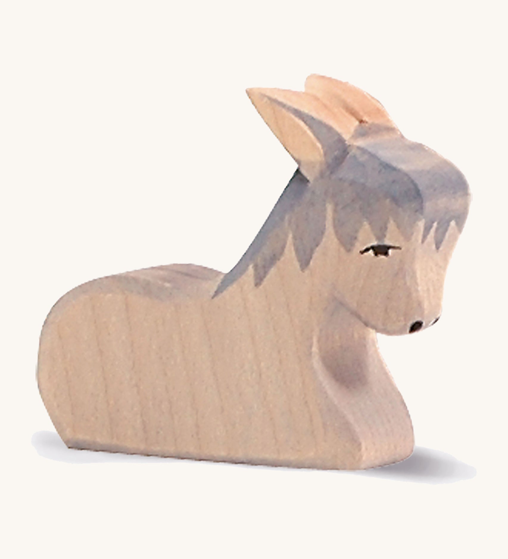 A grey wooden sitting Ostheimer donkey figure on a cream background.