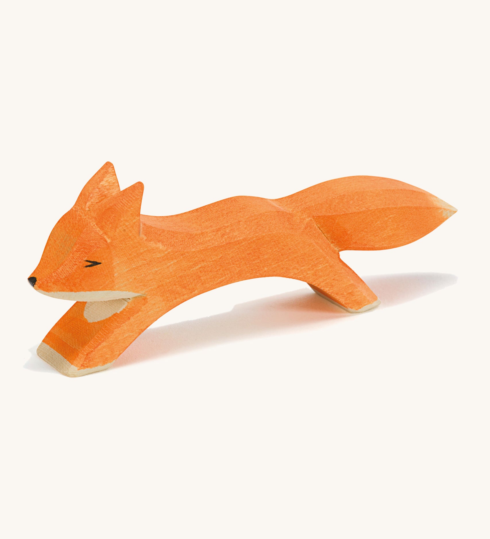 A wooden Ostheimer running fox figure on a cream background.