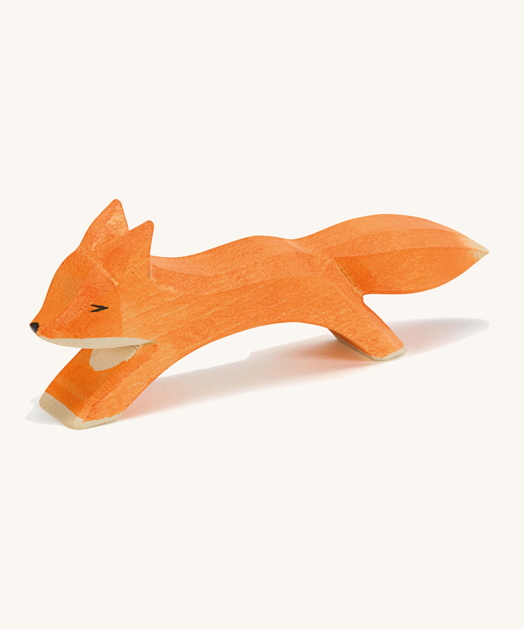 A wooden Ostheimer running fox figure on a cream background.