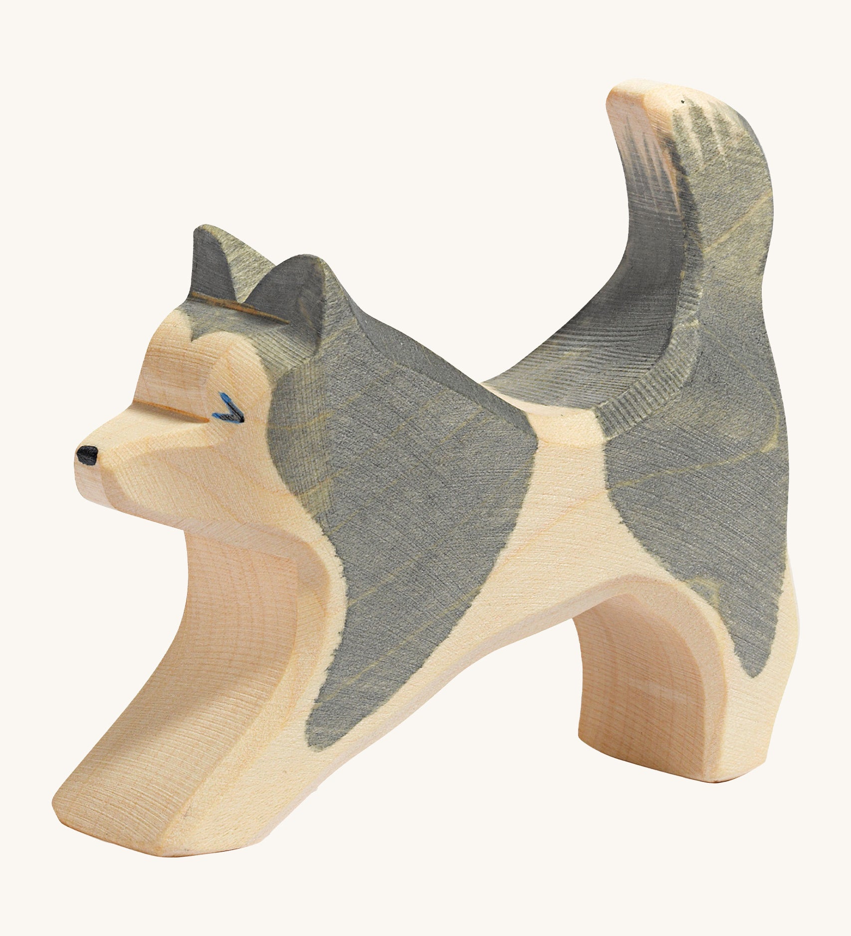 A grey and natural wooden Ostheimer running sled dog figure on a cream background.