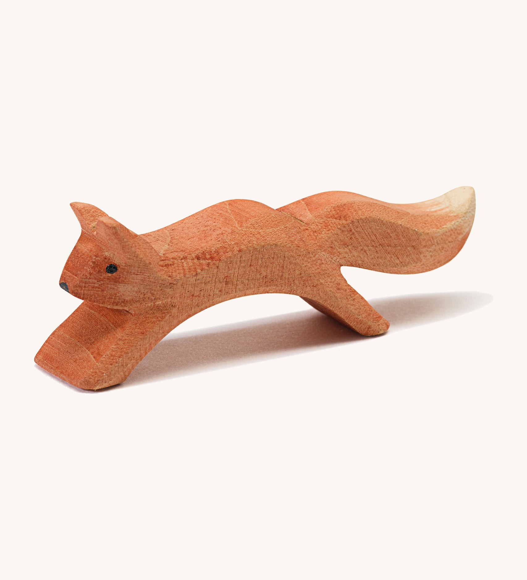 A wooden Ostheimer running squirrel figure on a cream background.