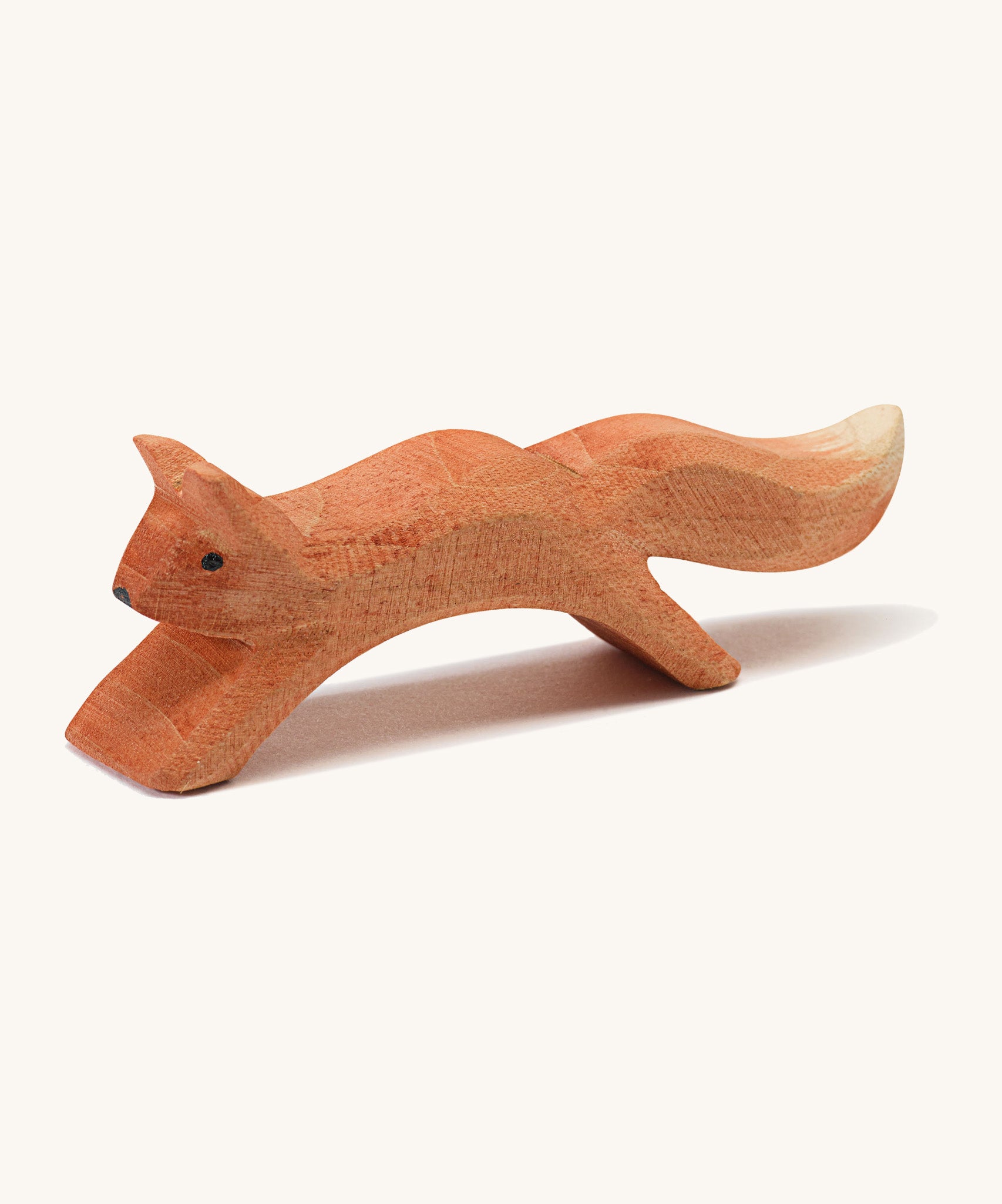 A wooden Ostheimer running squirrel figure on a cream background.