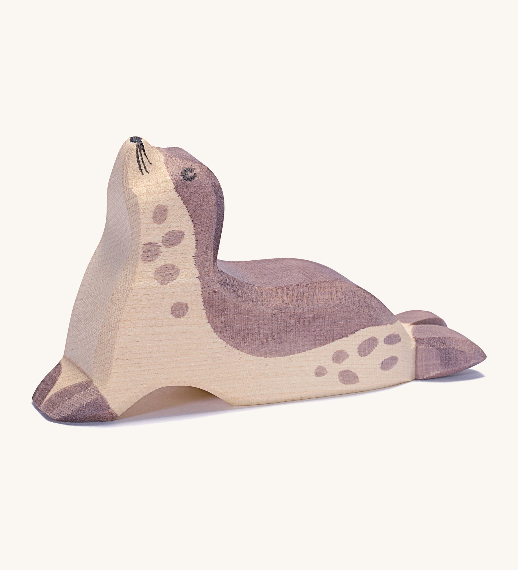 A wooden Ostheimer sea lion figure with its head held high on a cream background.