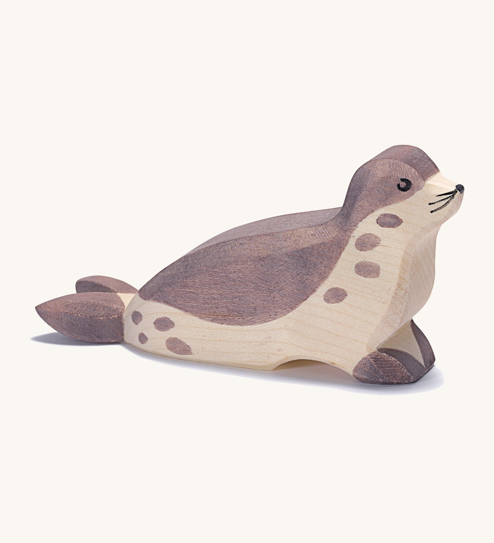 A wooden Ostheimer sea lion figure with its head low on a cream background.