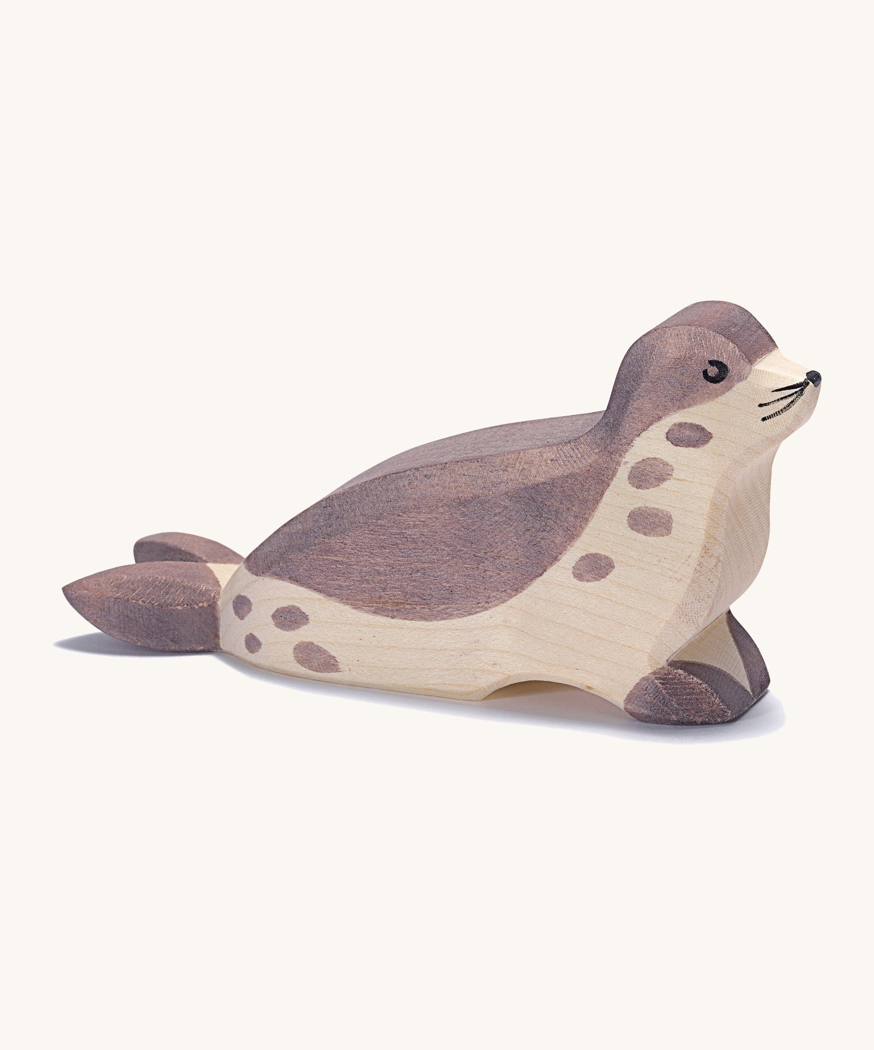 A wooden Ostheimer sea lion figure with its head low on a cream background.