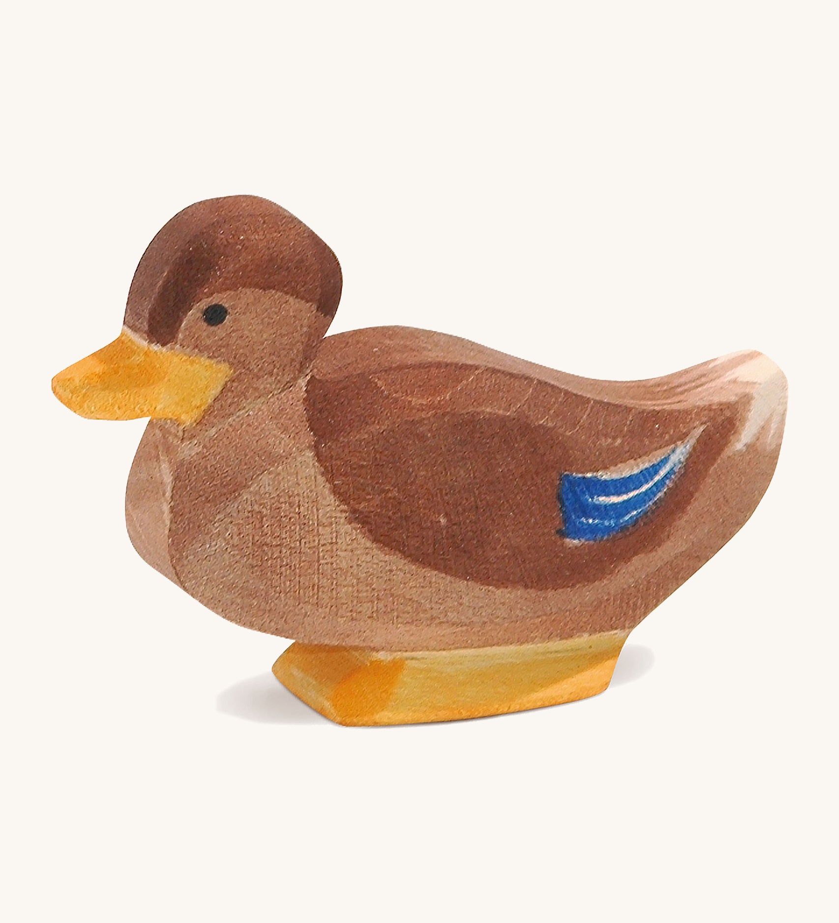 A brown wooden sitting Ostheimer duck figure on a cream background.