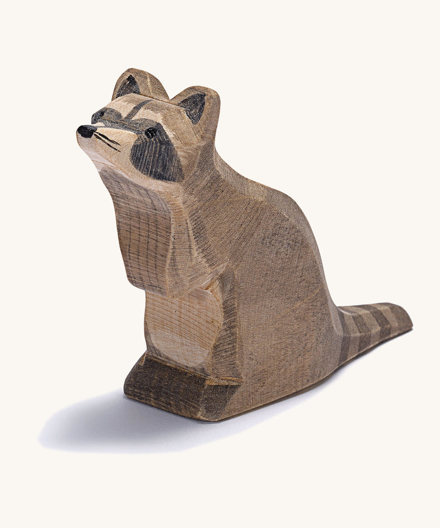 A wooden Ostheimer sitting raccoon figure on a cream background.