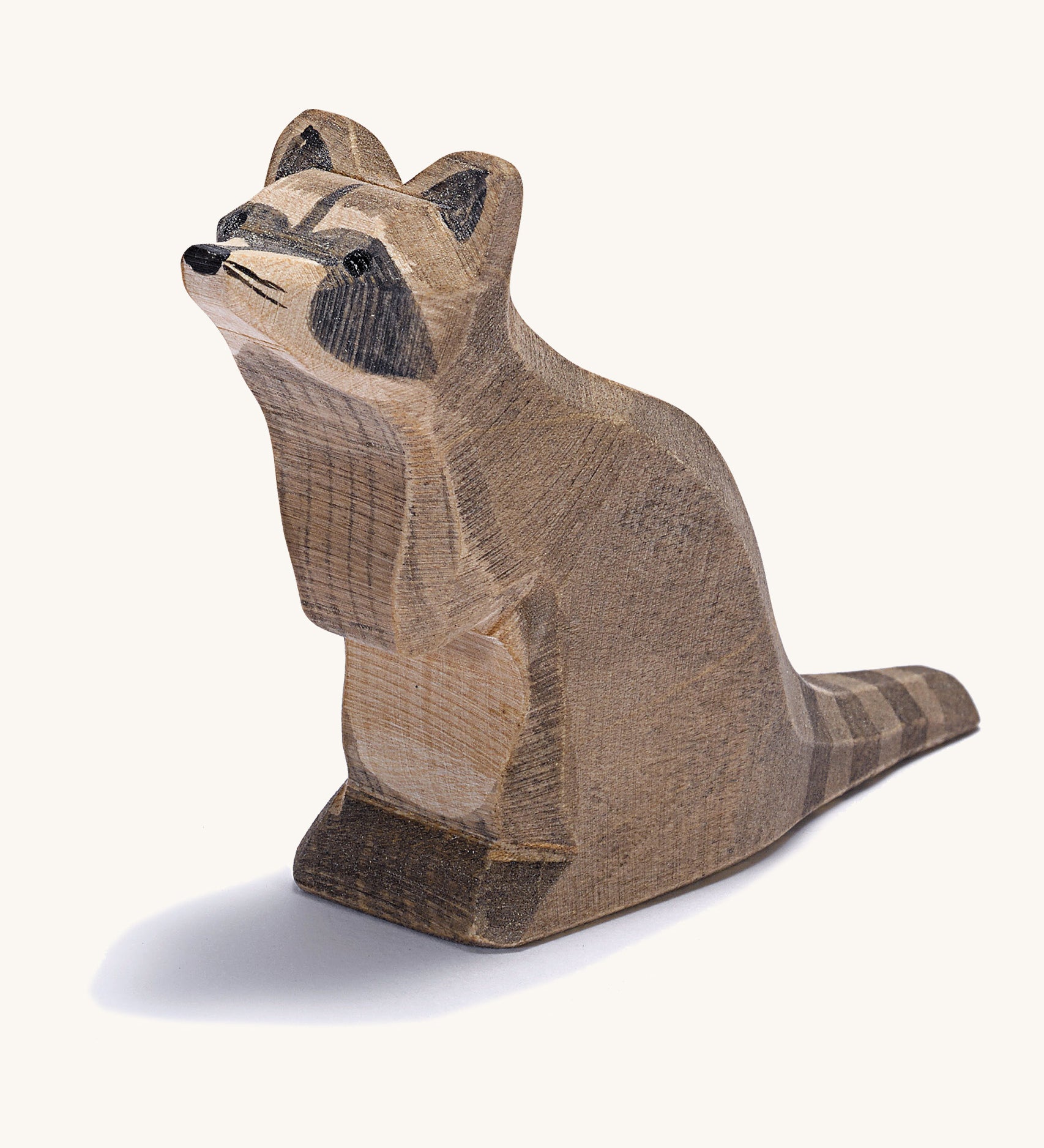 A wooden Ostheimer sitting raccoon figure on a cream background.