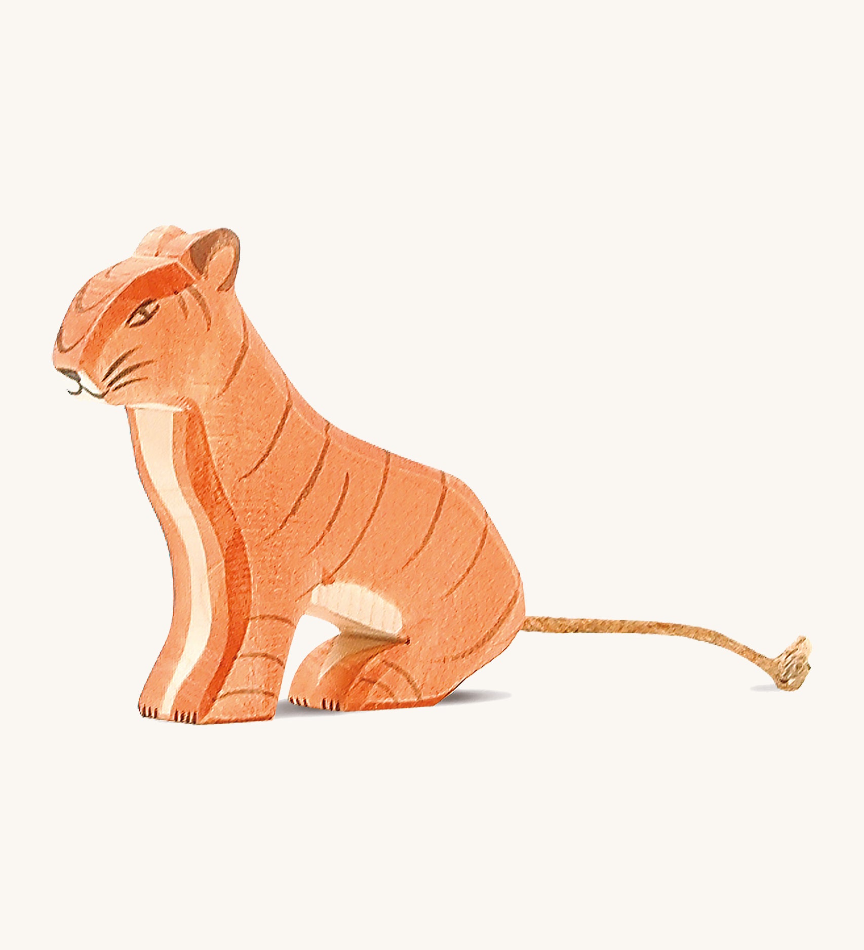 A wooden sitting Ostheimer tiger figure on a cream background.