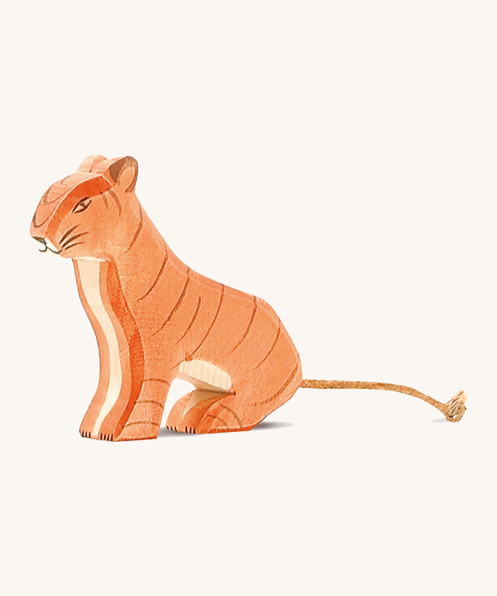 A wooden sitting Ostheimer tiger figure on a cream background.