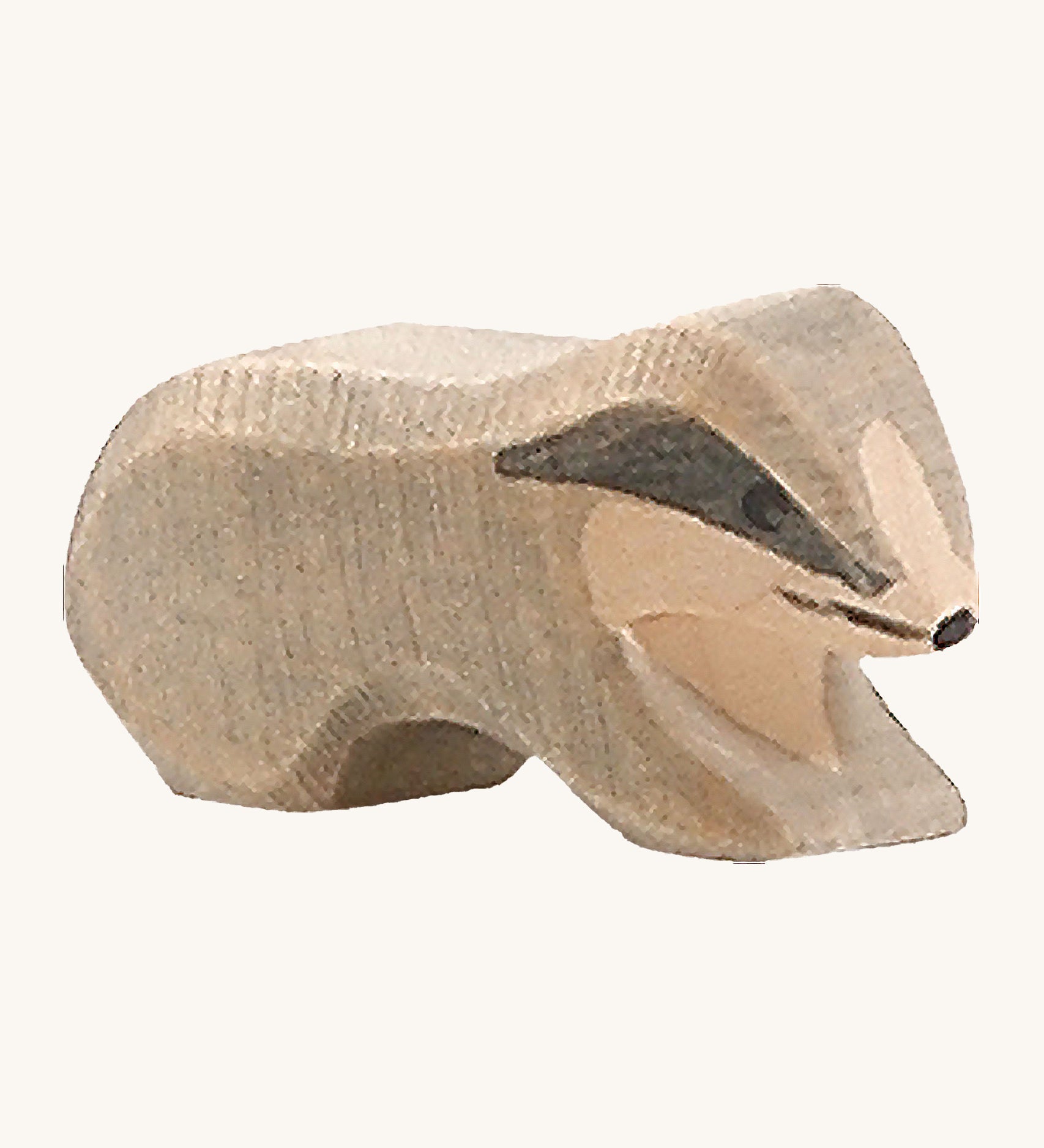 A small wooden Ostheimer badger figure on a cream background.