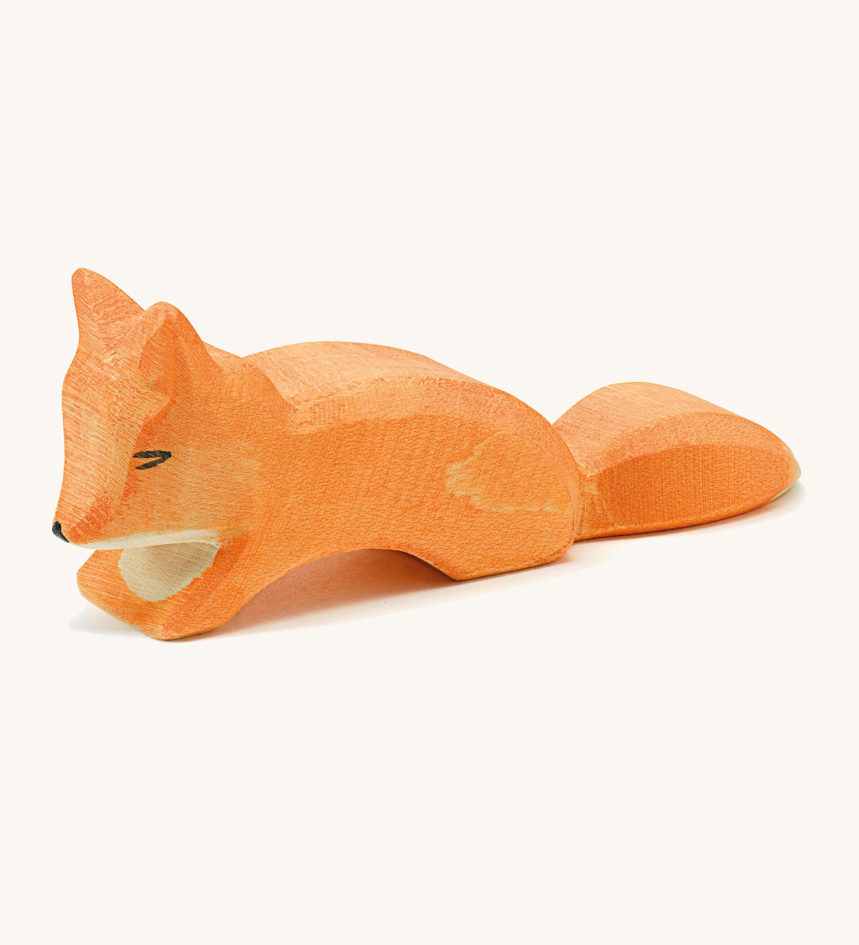 A small wooden Ostheimer creepng fox figure on a cream background.