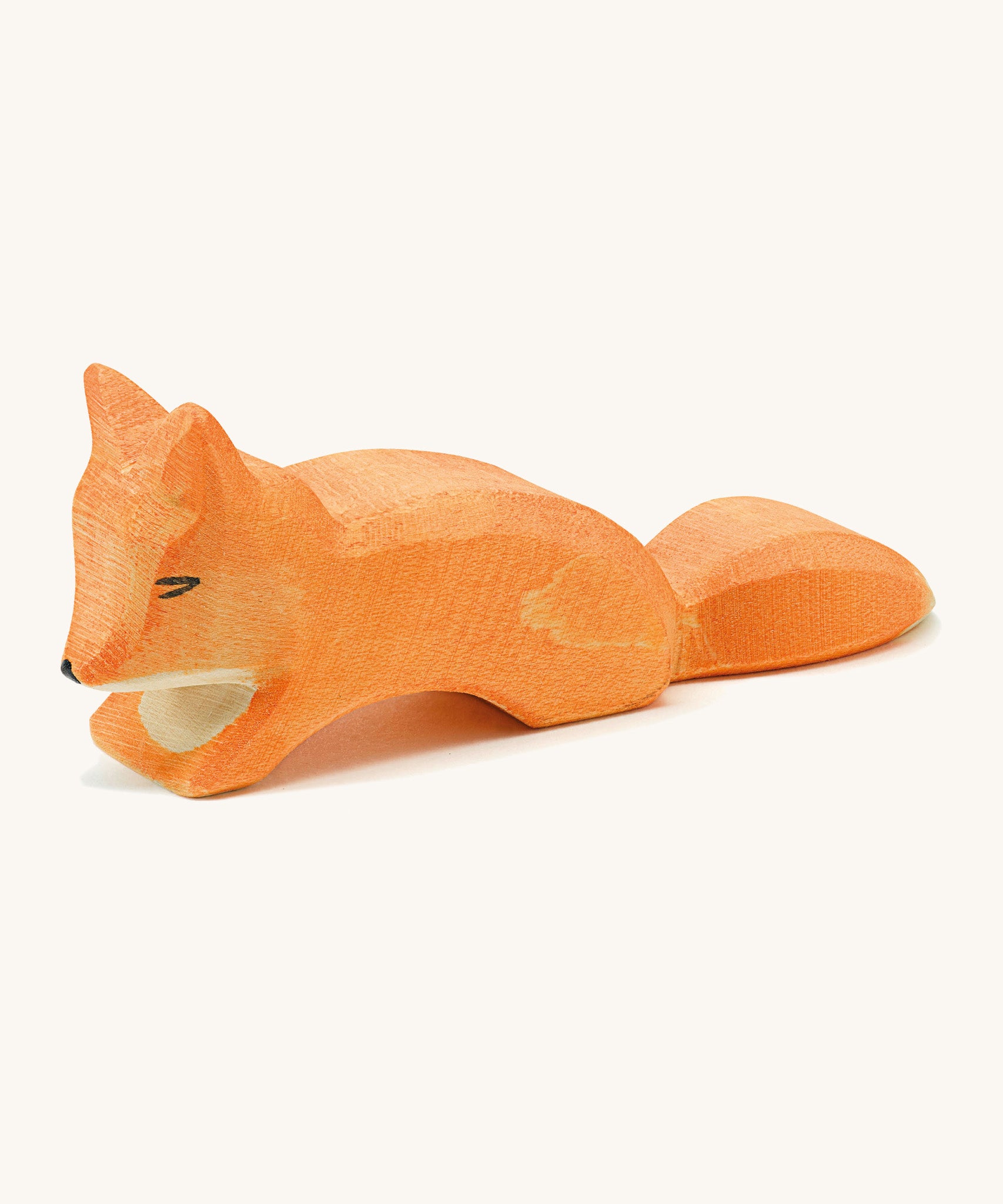 A small wooden Ostheimer creepng fox figure on a cream background.