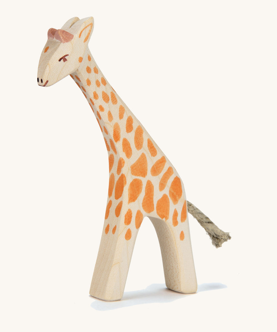 A wooden small Ostheimer giraffe with. head low on a cream background