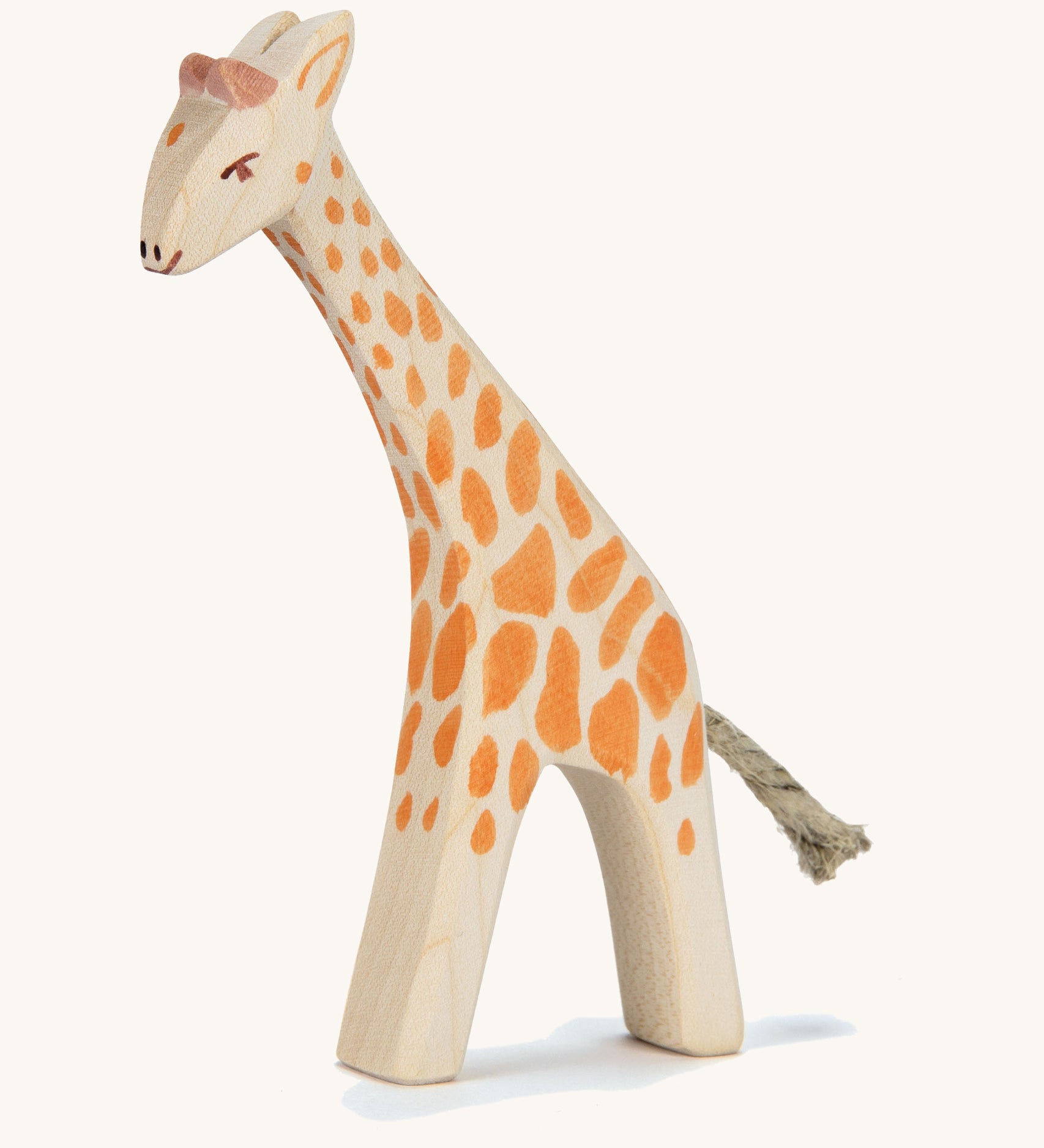 A wooden small Ostheimer giraffe with. head low on a cream background