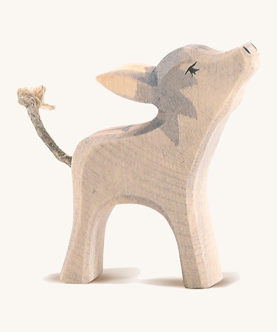 A small grey wooden Ostheimer donkey with its head held high on a cream background.