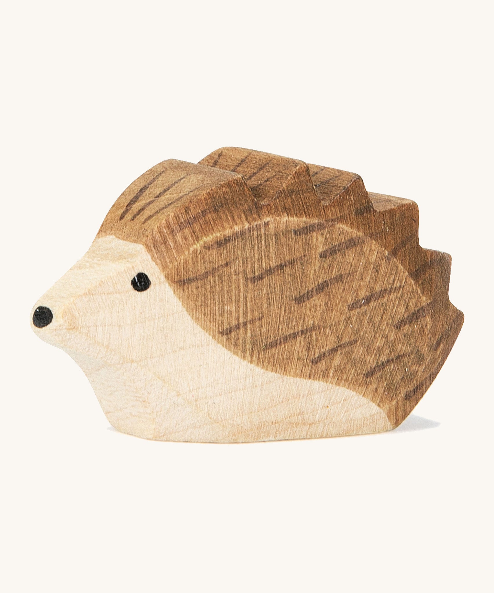 A small wooden Ostheimer hedgehog figure on a cream background.