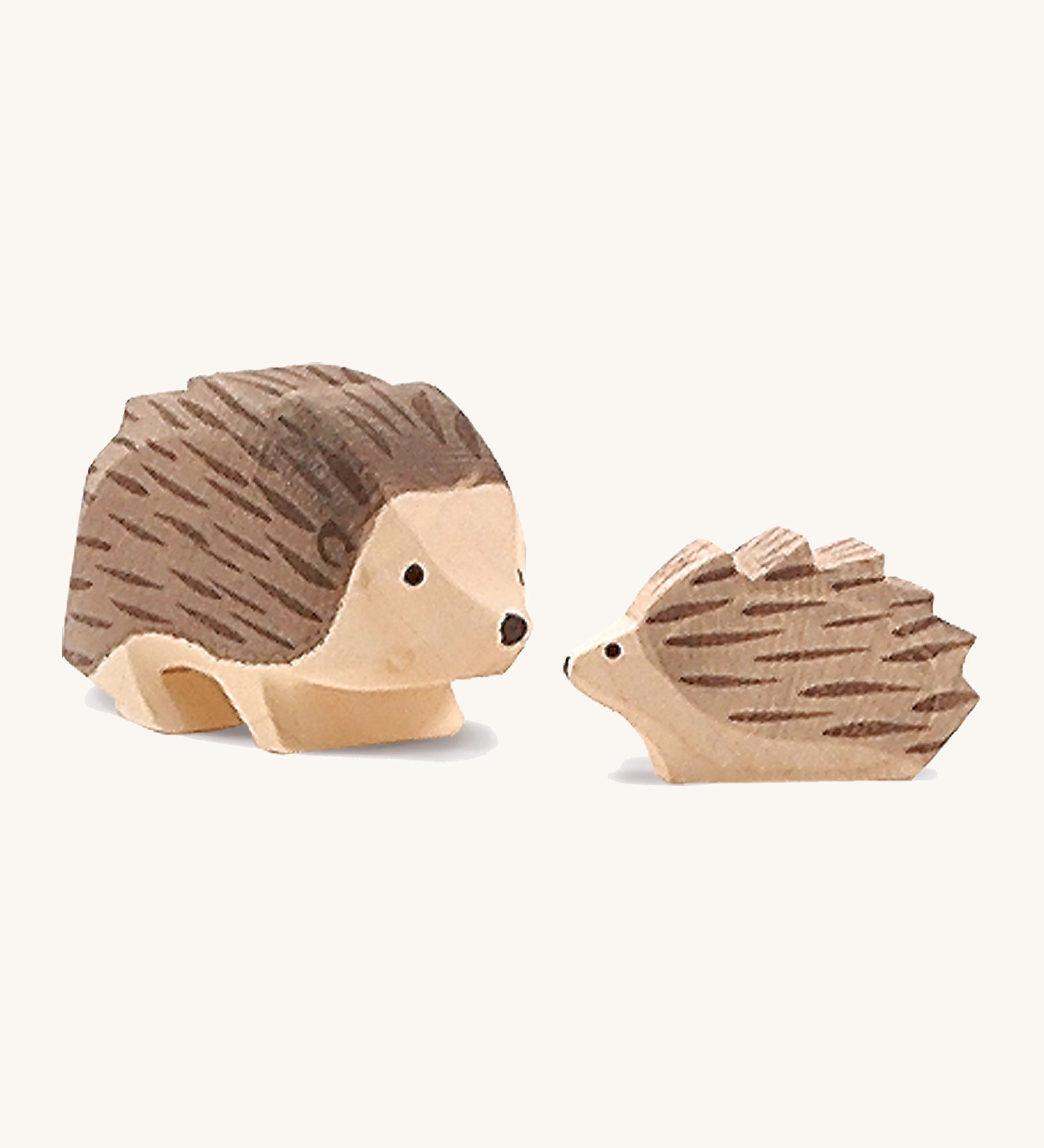 A small wooden Ostheimer hedgehog figure standing next to a large wooden Ostheimer hedgehog figure on a cream background.