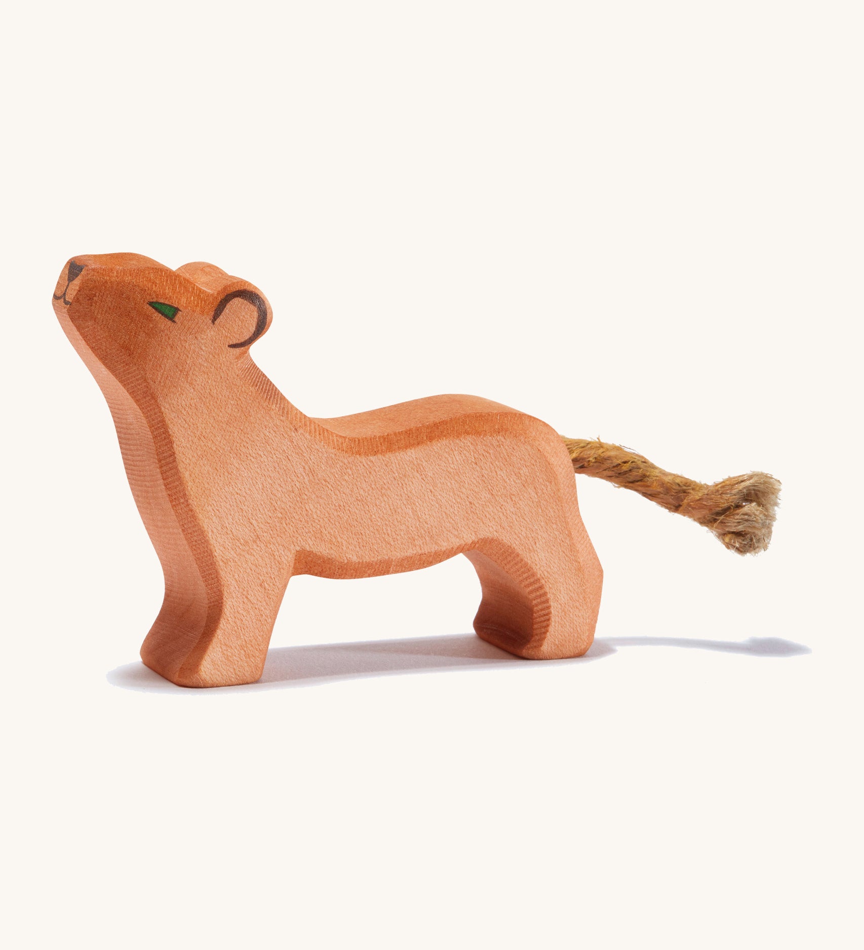 A small wooden Ostheimer lion with its head held high on a cream background.