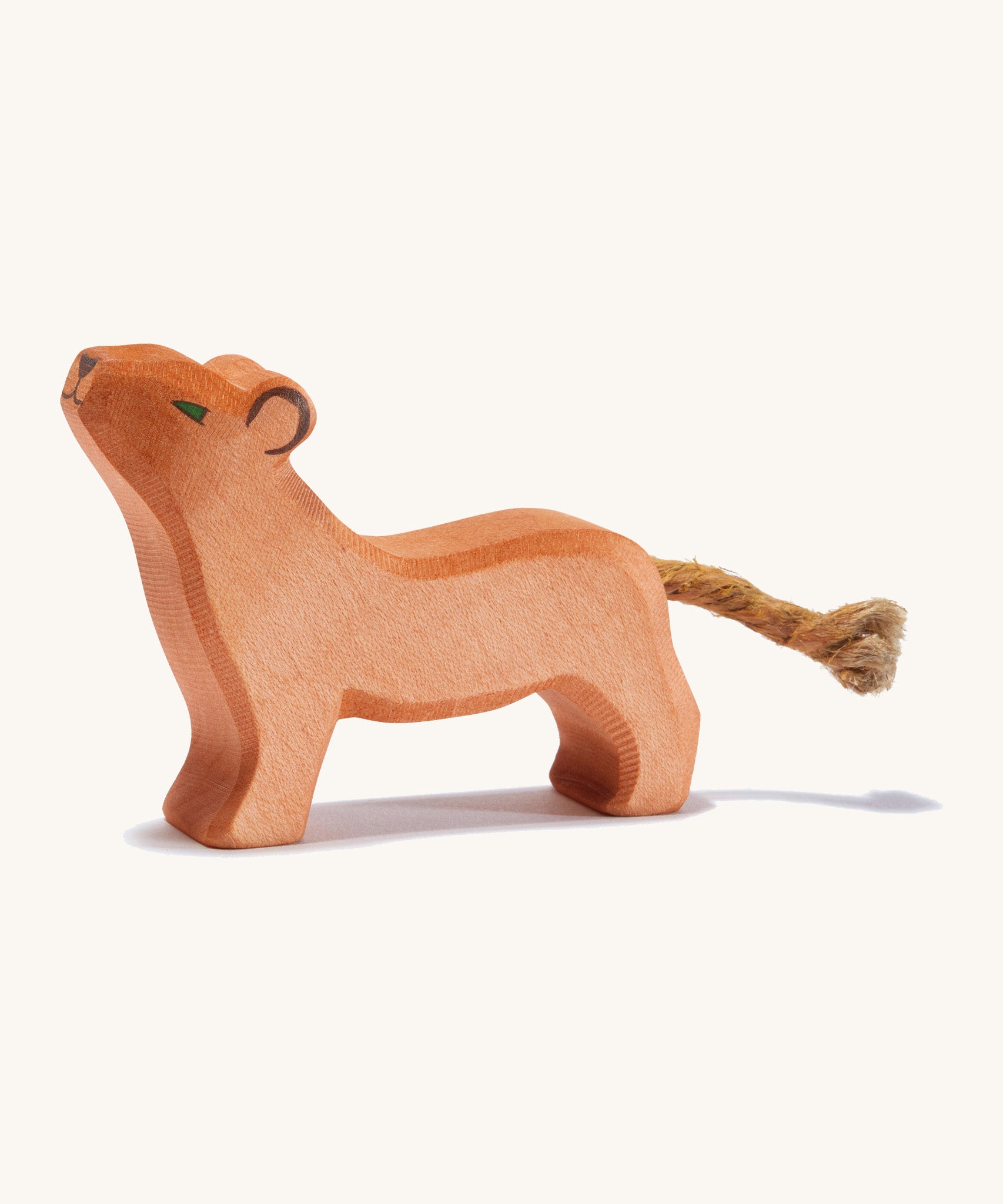 A small wooden Ostheimer lion with its head held high on a cream background.