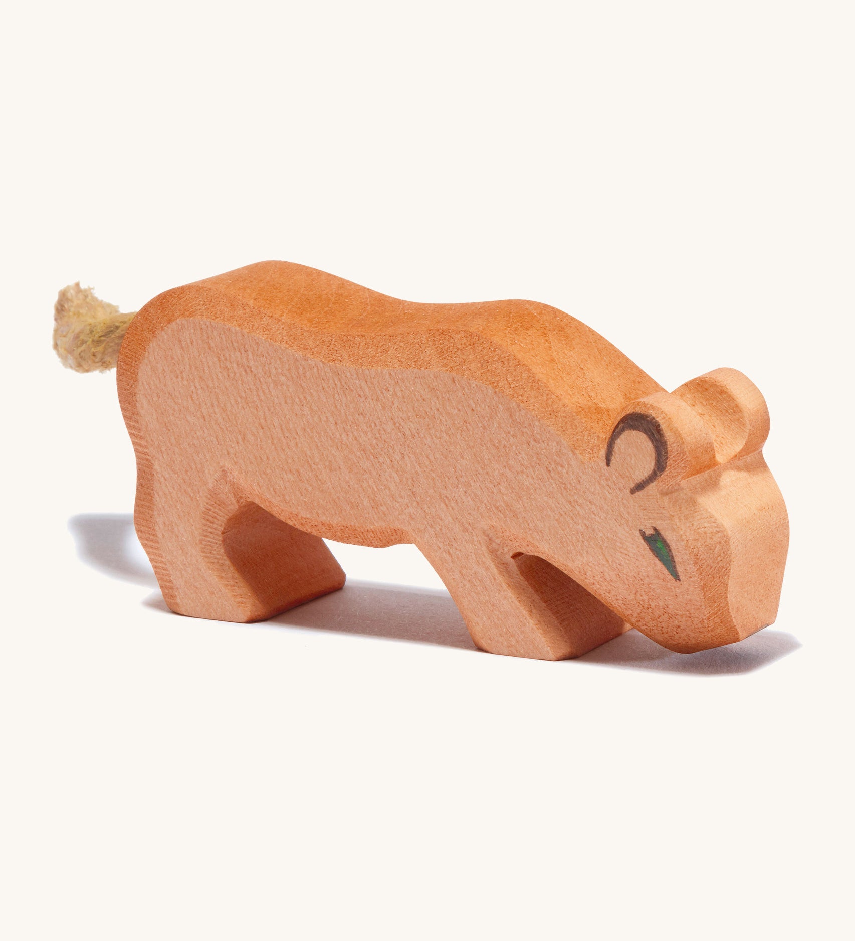 A small wooden Ostheimer lion with its head low on a cream background.