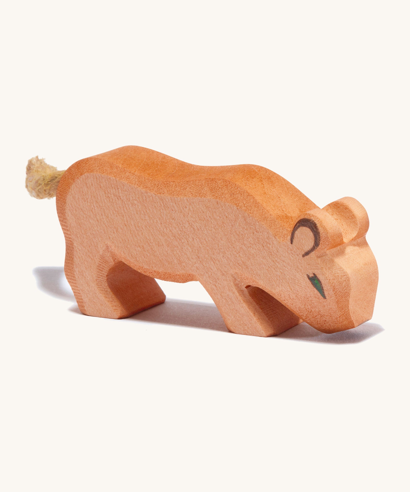 A small wooden Ostheimer lion with its head low on a cream background.