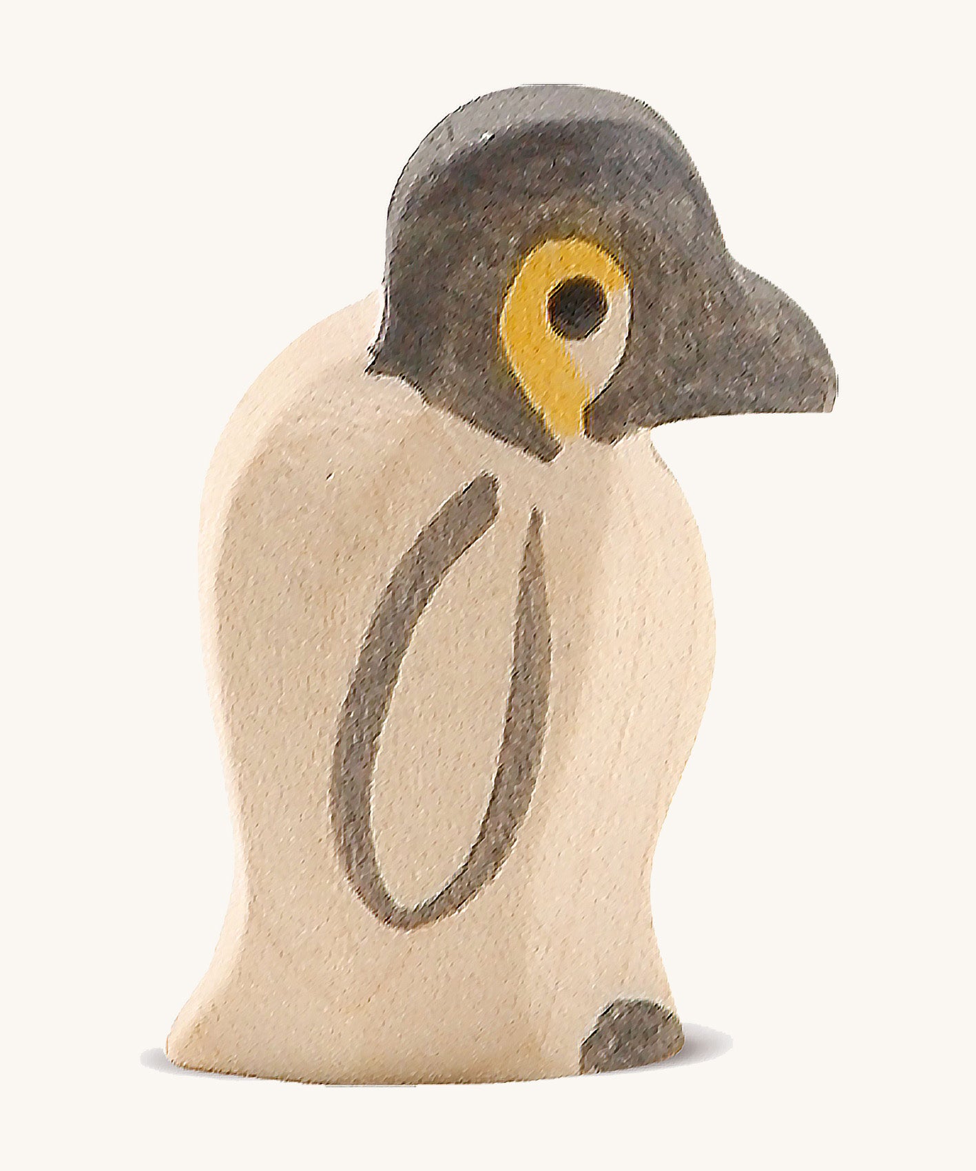 A small wooden Ostheimer penguin figure on a cream background.