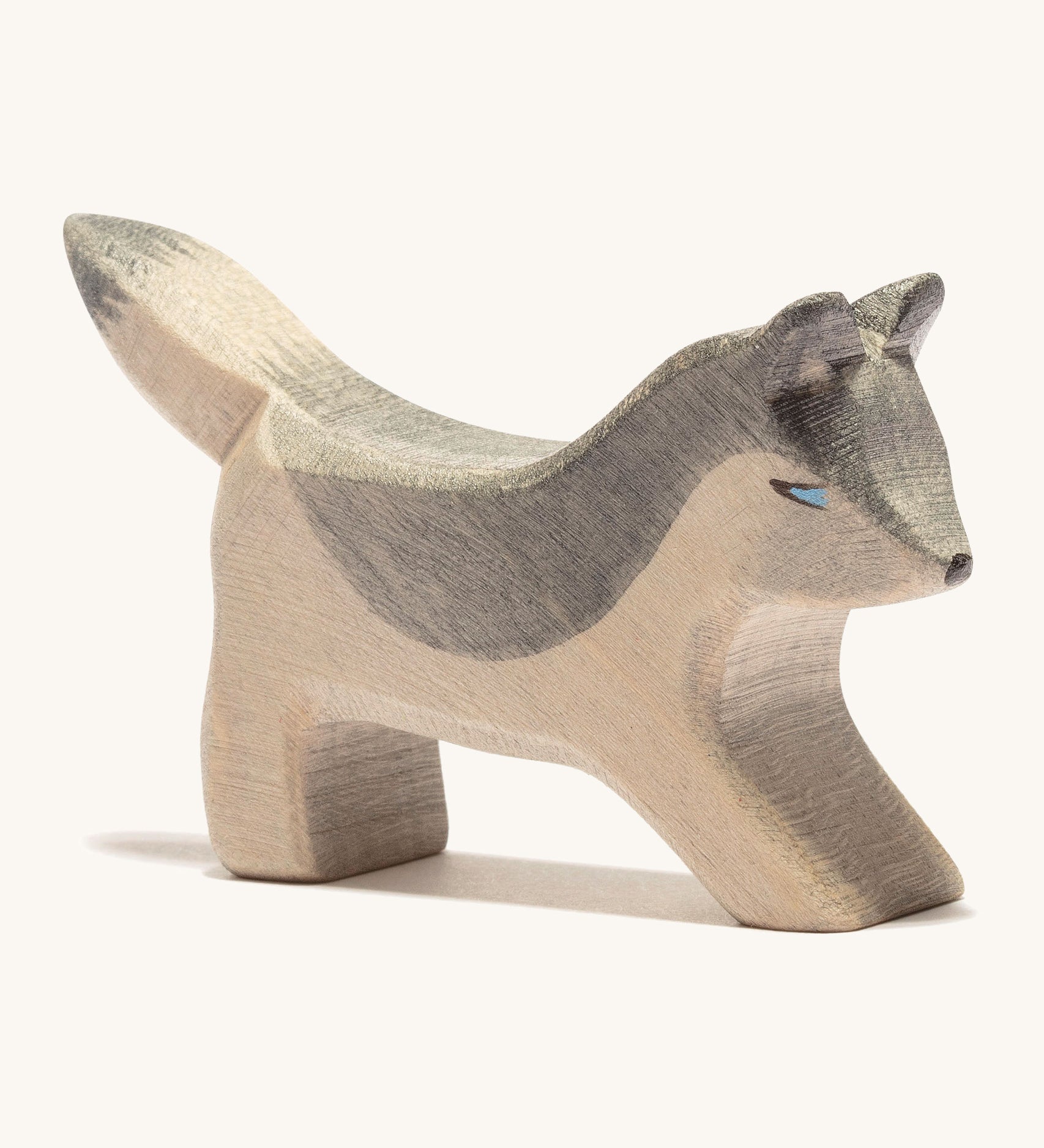 A small wooden Ostheimer wolf playing, on a cream background.